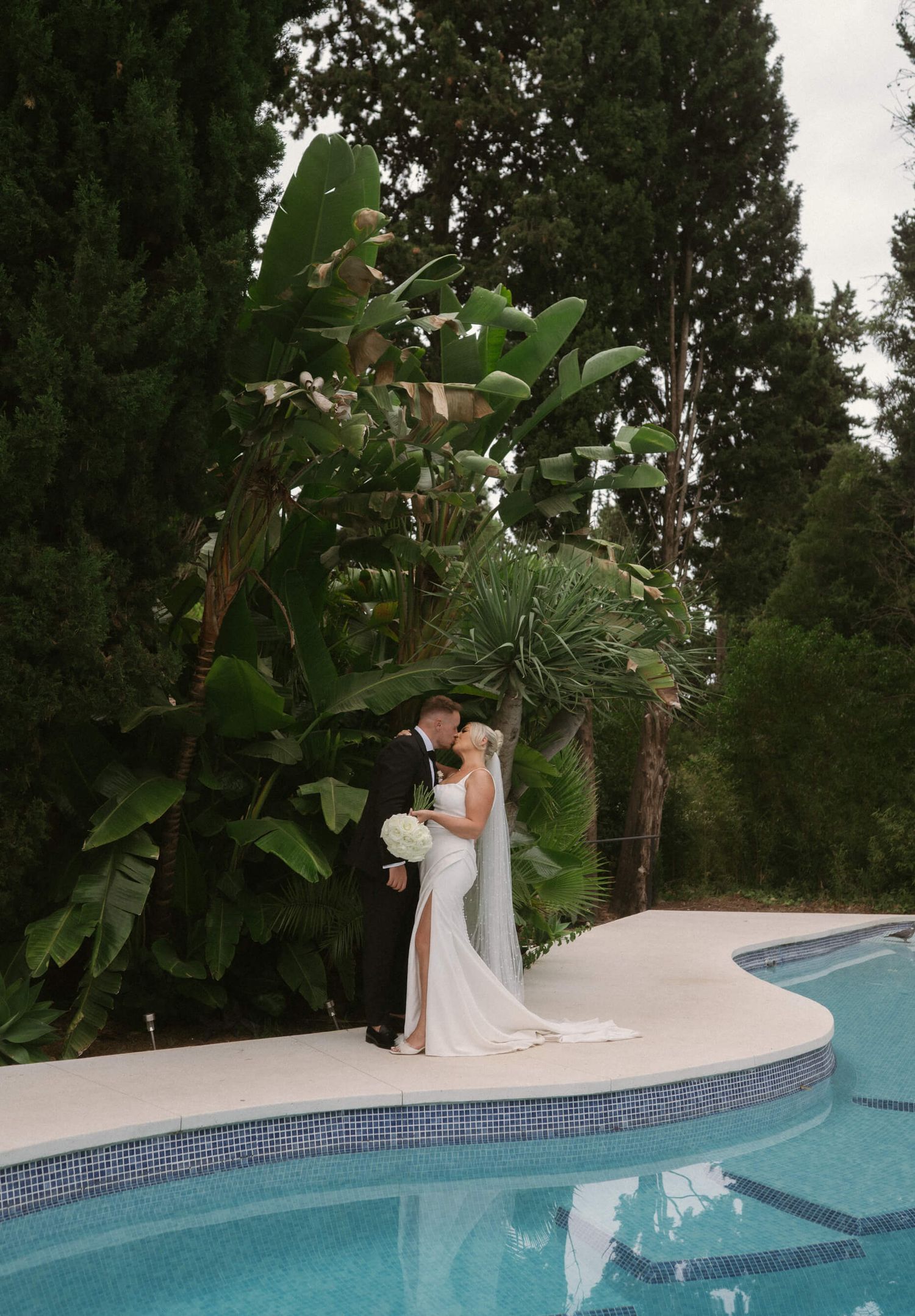 Couple shares intimate moment by poolside during sunset wedding photoshoot.
