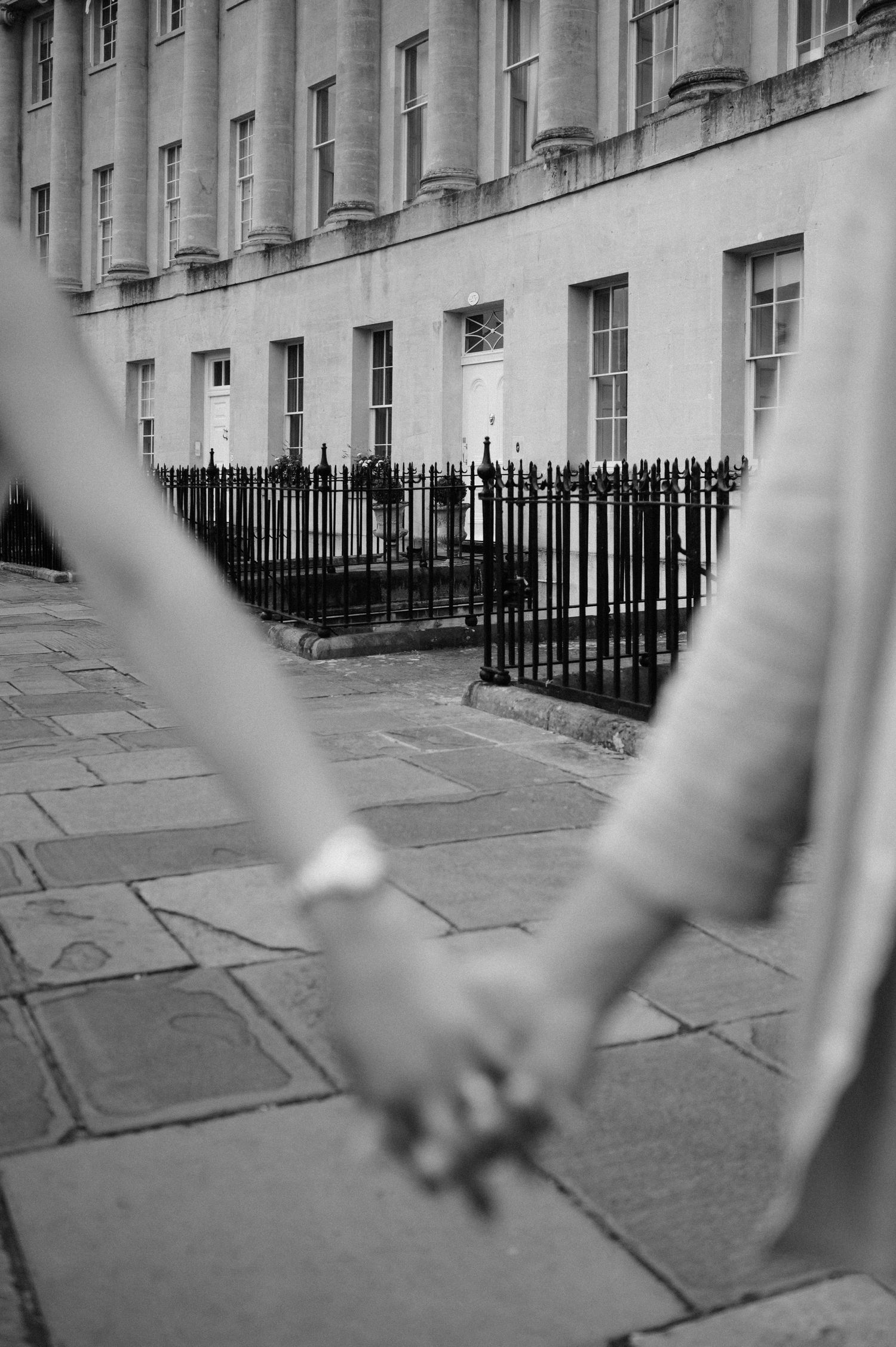 Close-up shot of intertwined hands against historic Georgian architecture.