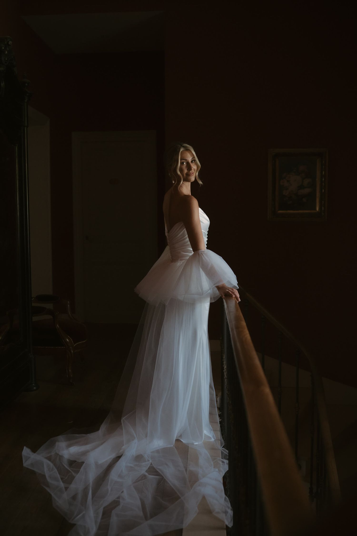 Ethereal bridal gown with flowing tulle skirt captured in dramatic low-light setting.