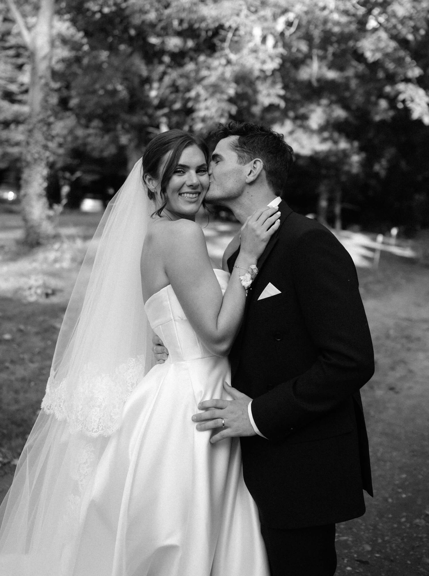 Black and white romantic wedding portrait captured in a garden setting.