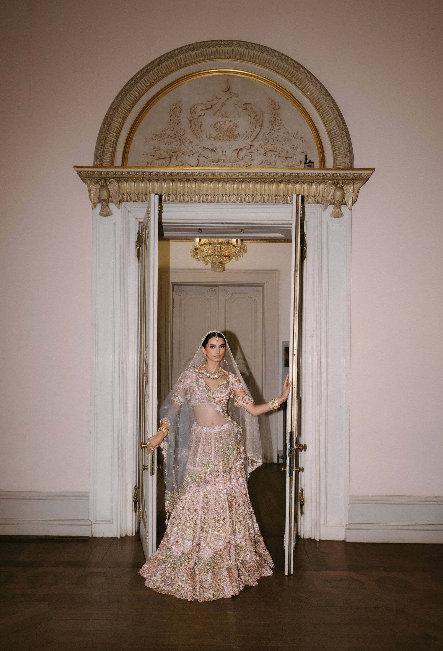 Ornate doorways and architectural details frame an elegant bridal scene in a historic interior.