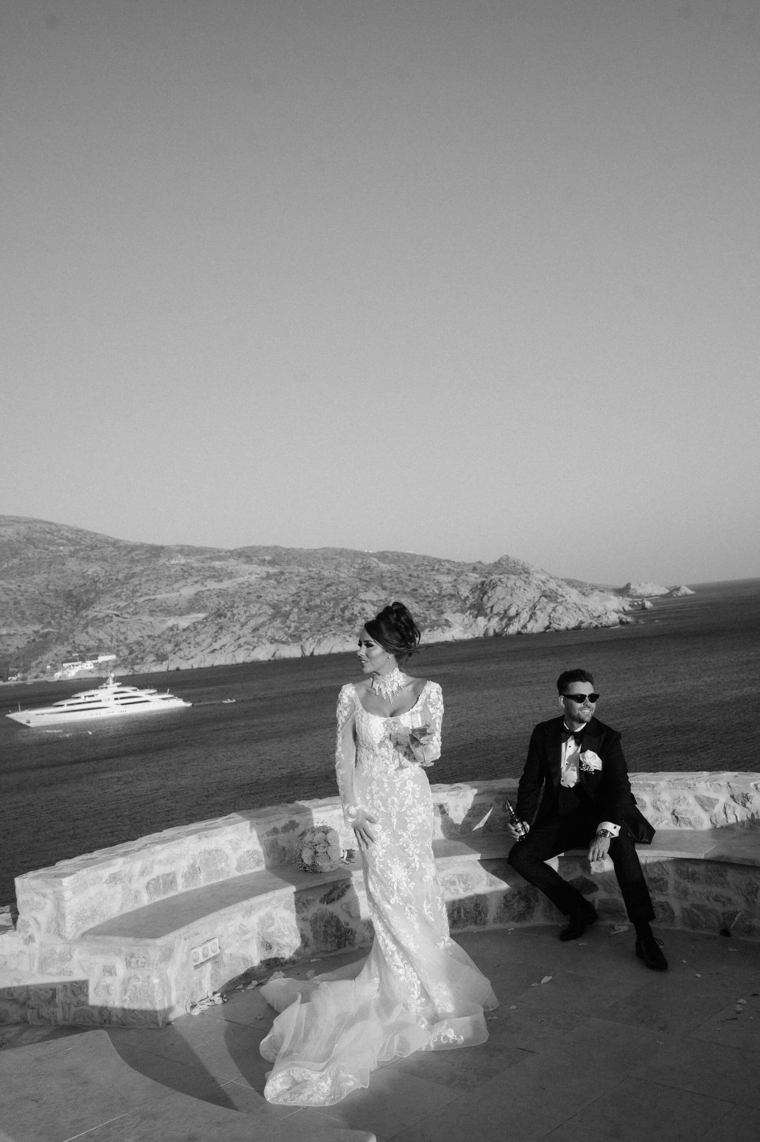 A black and white wedding photo captured against a scenic coastal landscape.