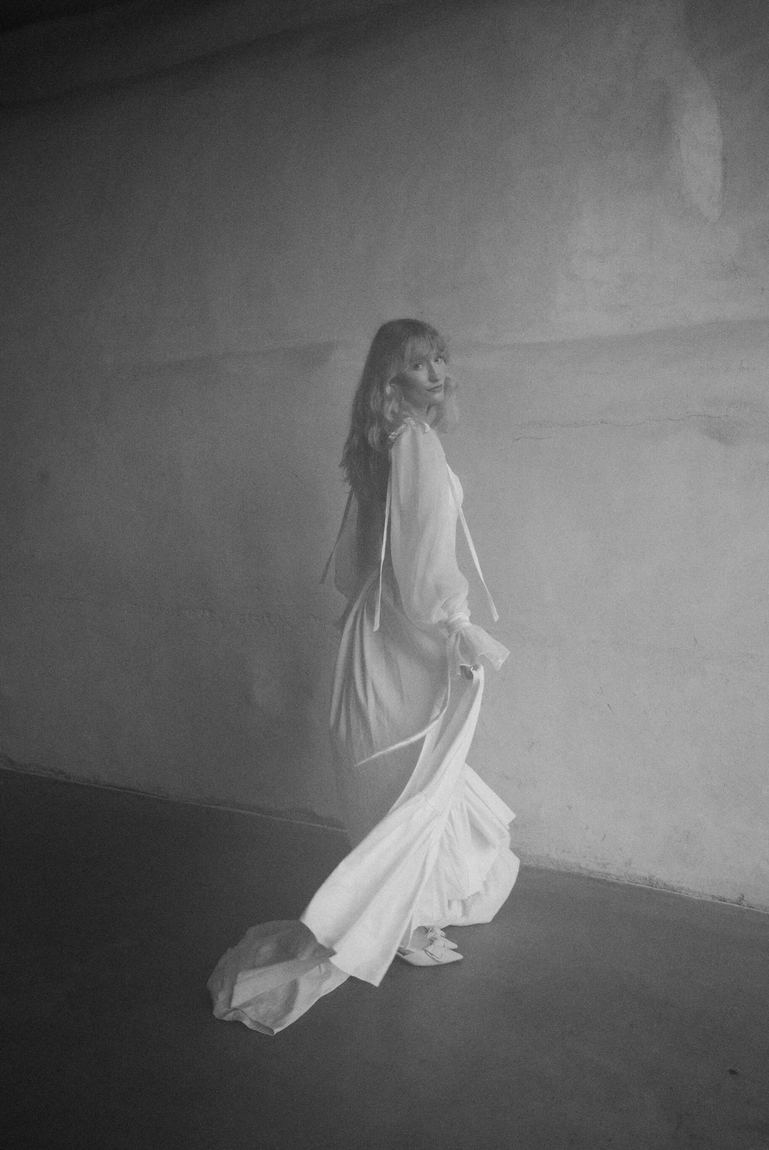 Artistic black and white photos of flowing white fabric in motion against dark background.