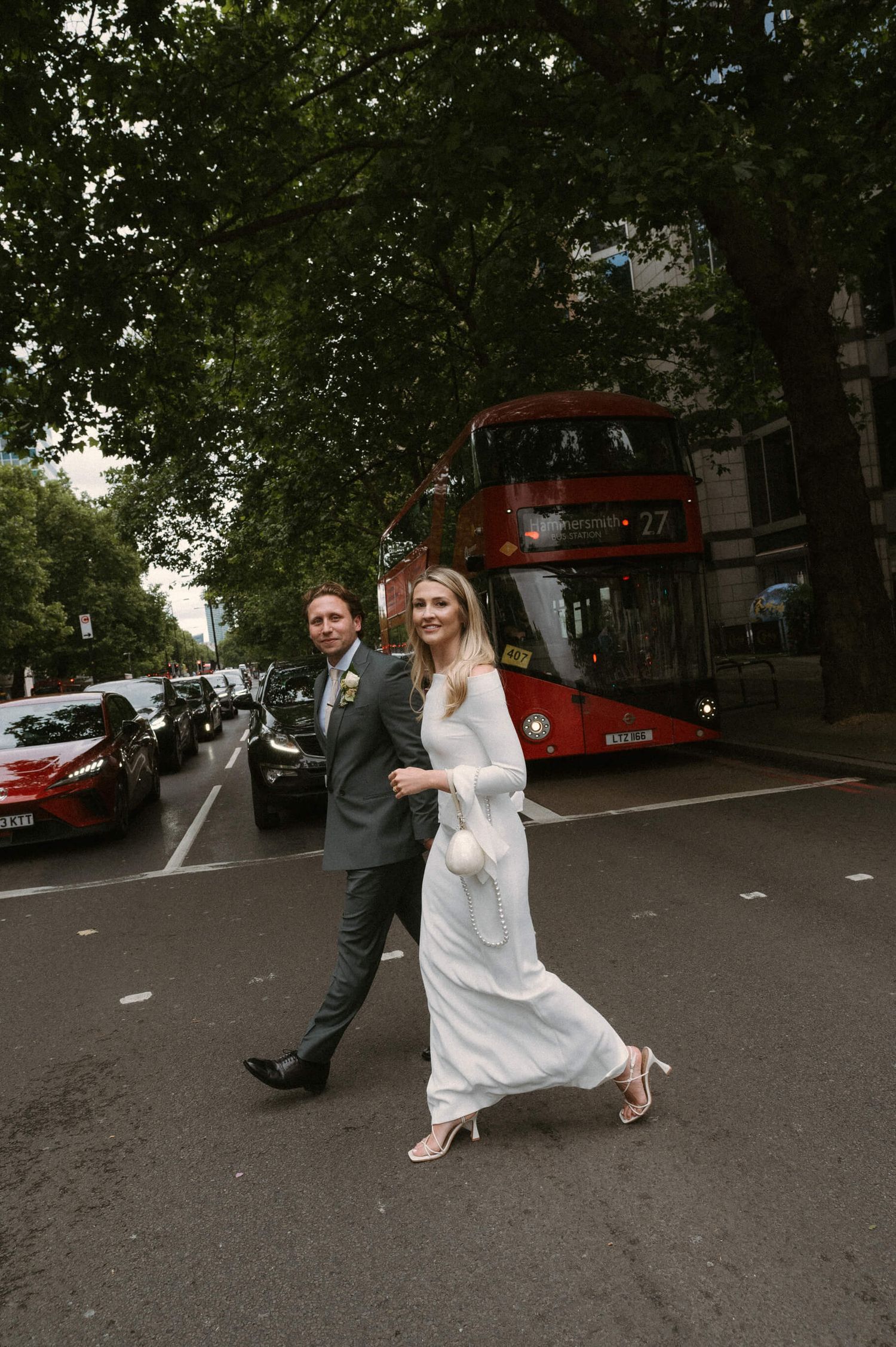 Playful wedding photo on a London street with red double-decker bus in the background.