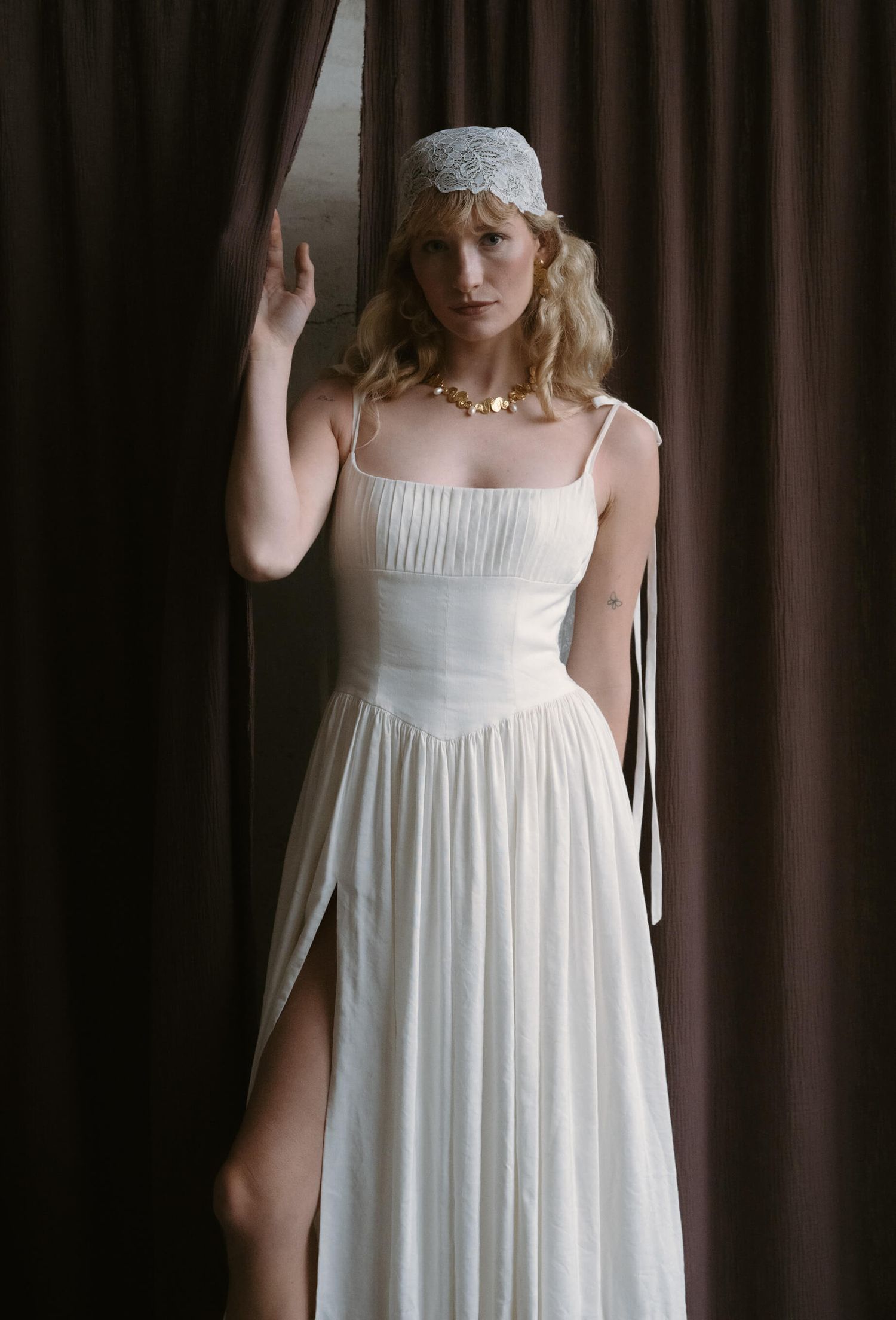 White empire waist nightgown style dress photographed against dark curtain backdrop.