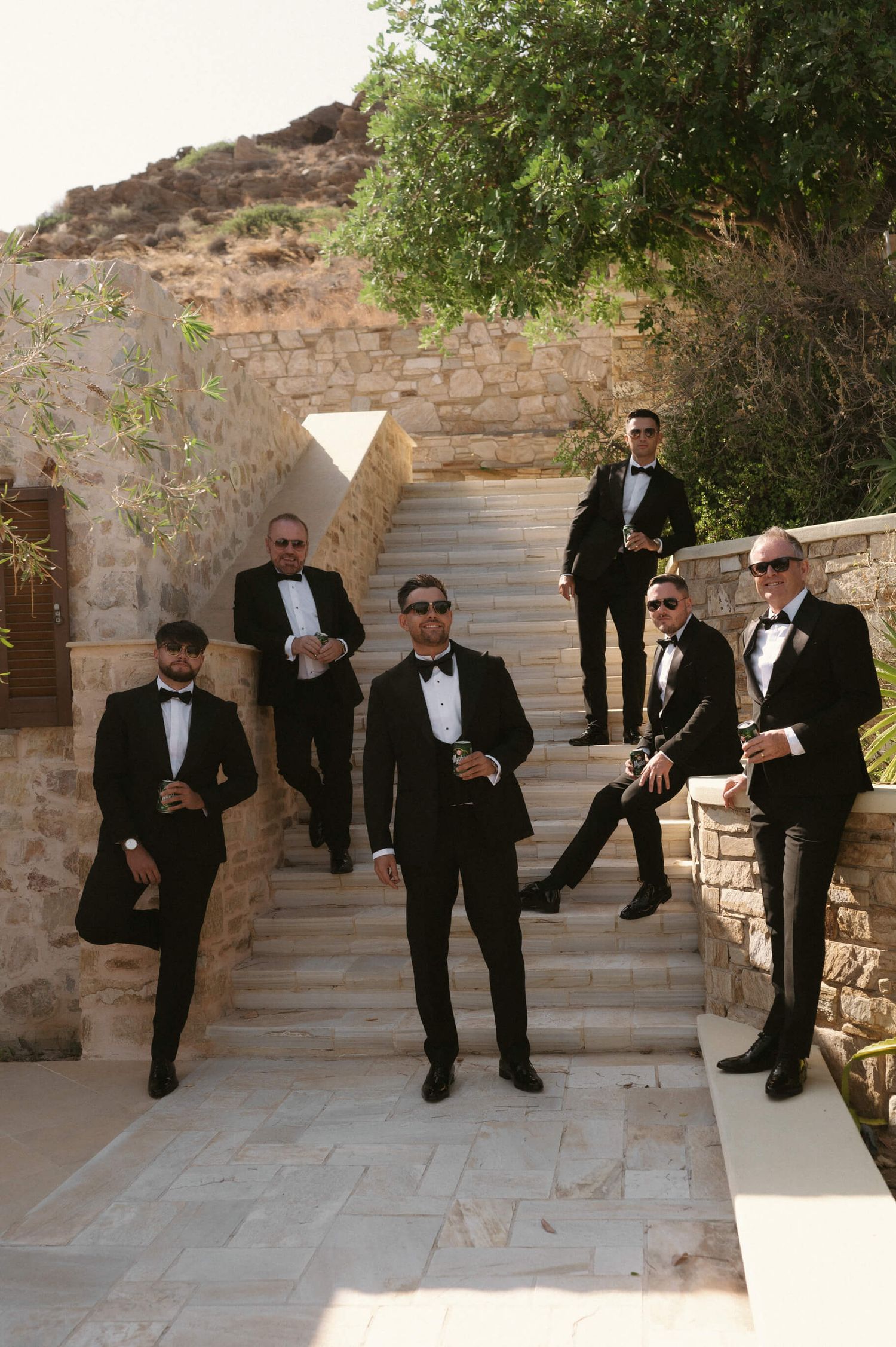 A group in formal attire poses on stone steps against an ancient architectural backdrop.