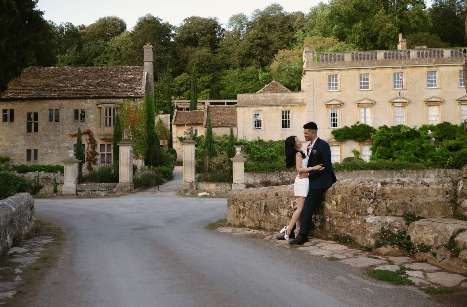 Wedding couple poses for romantic photos along a historic stone building exterior.