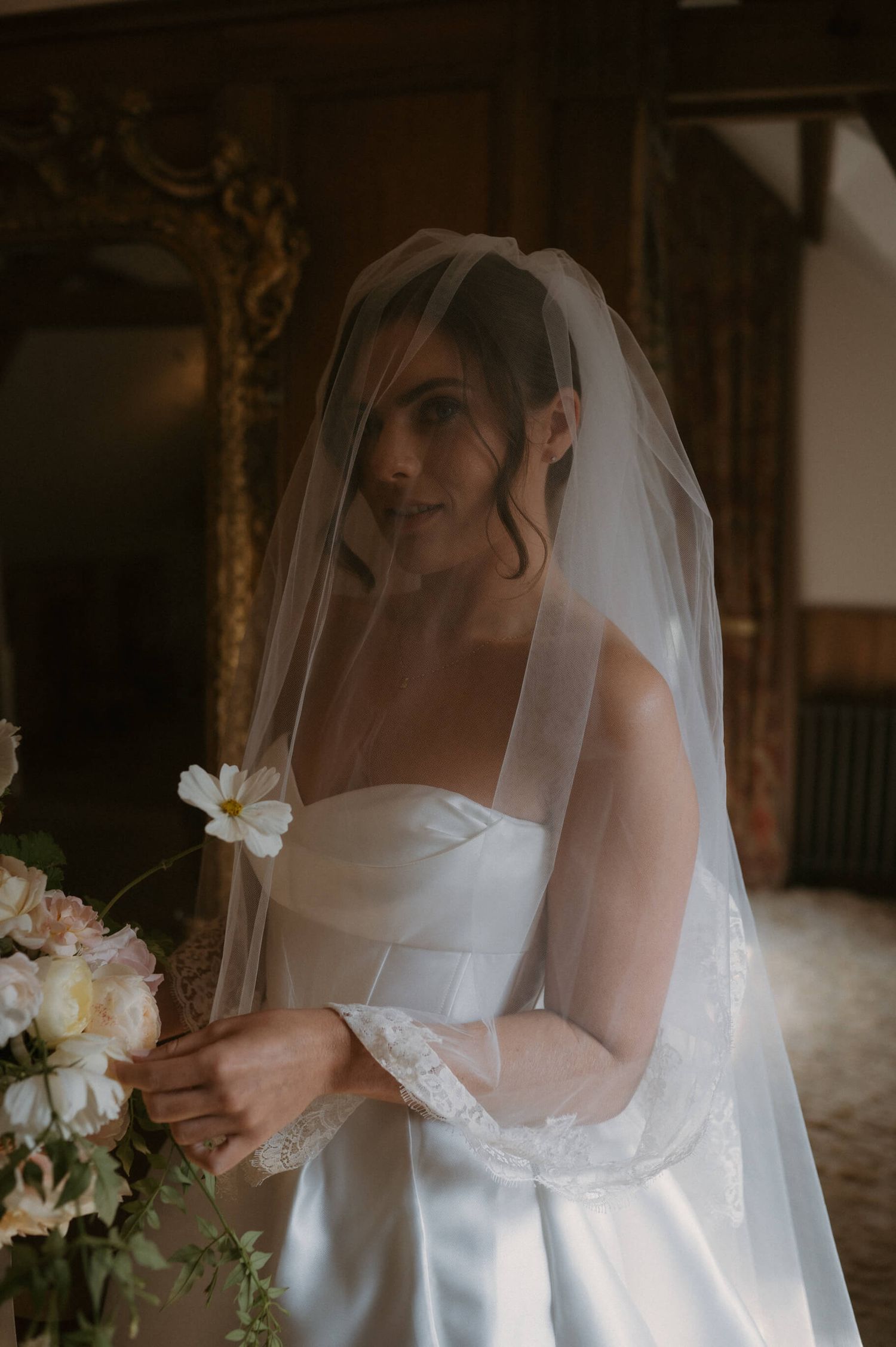 Delicate bridal portrait with white flowers and veil in soft natural light.