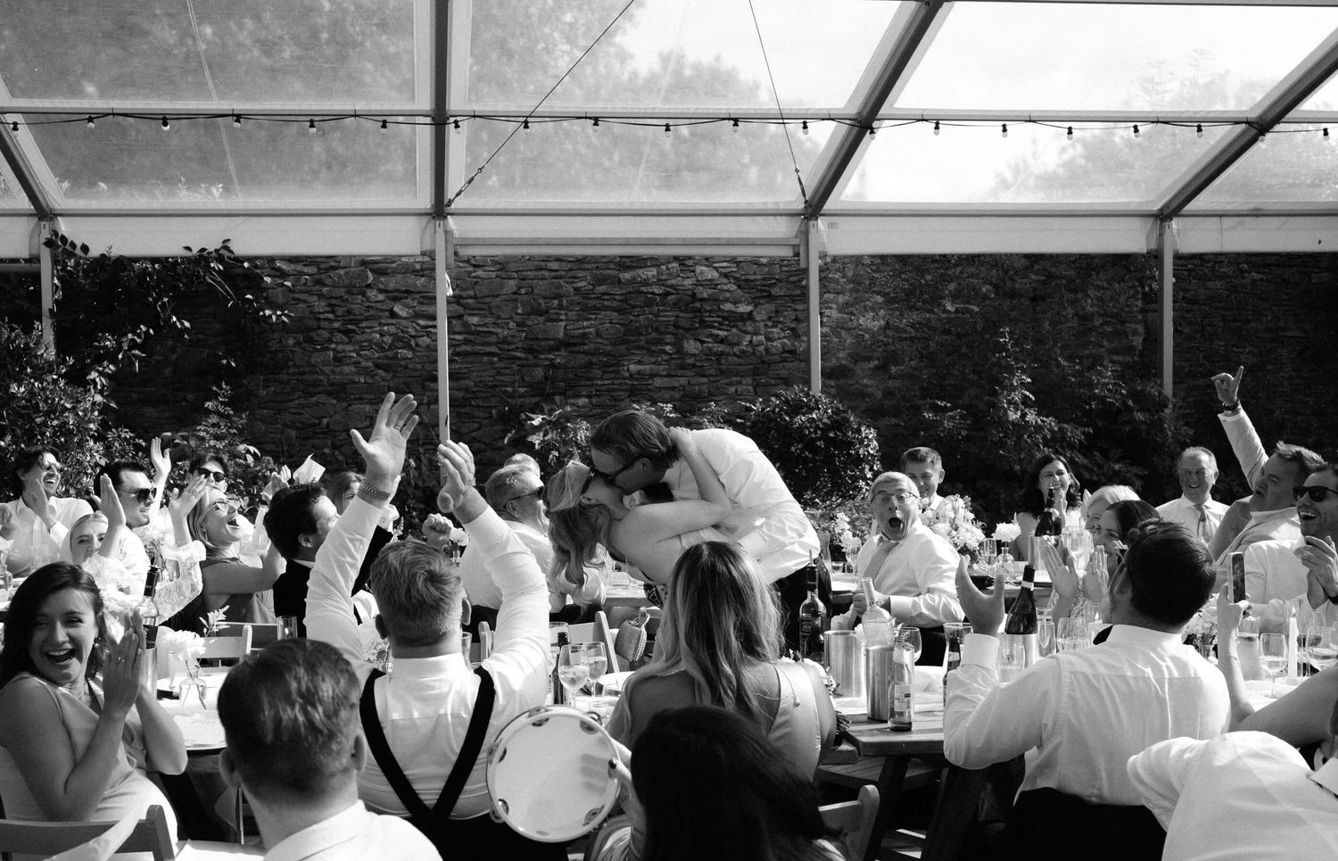 Black and white panorama of a crowded wedding ceremony audience under a covered venue.