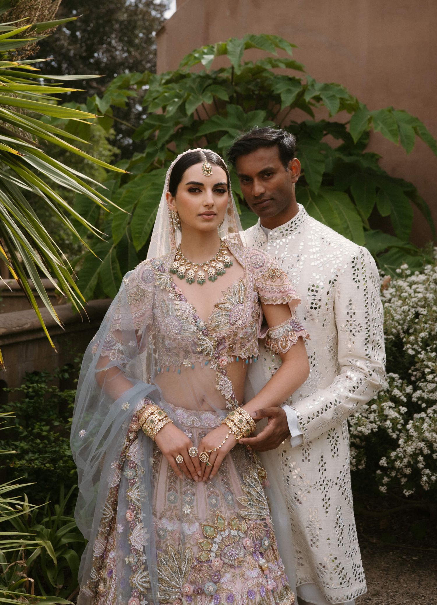Elegant South Asian wedding attire featuring intricate embroidery and traditional designs in a garden setting.