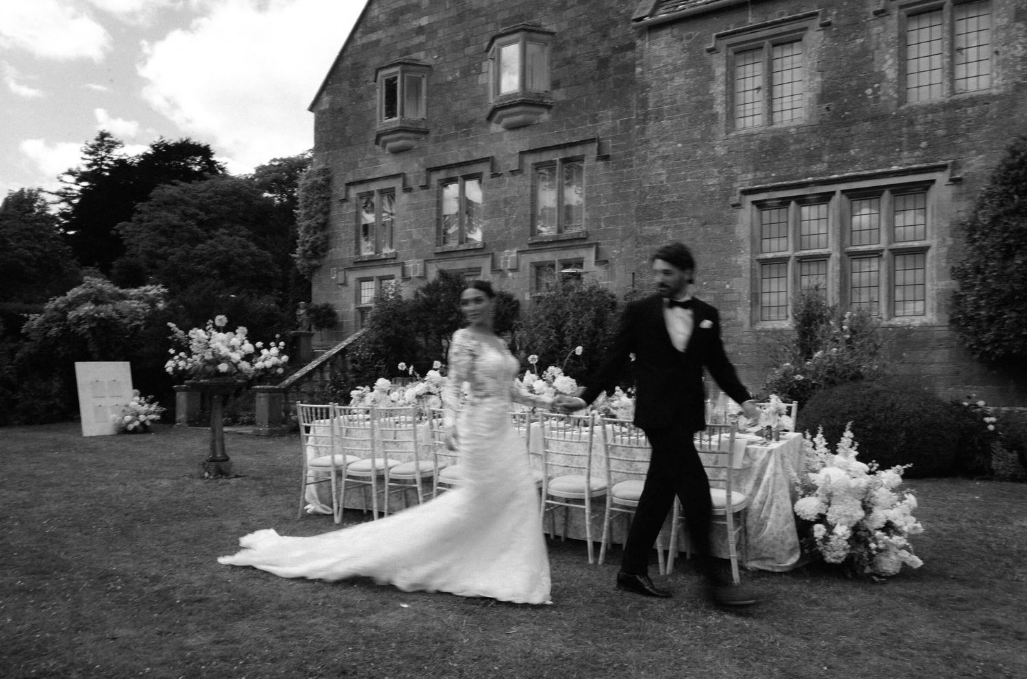Wedding reception setup outside a grand historic stone mansion with elegant table settings.