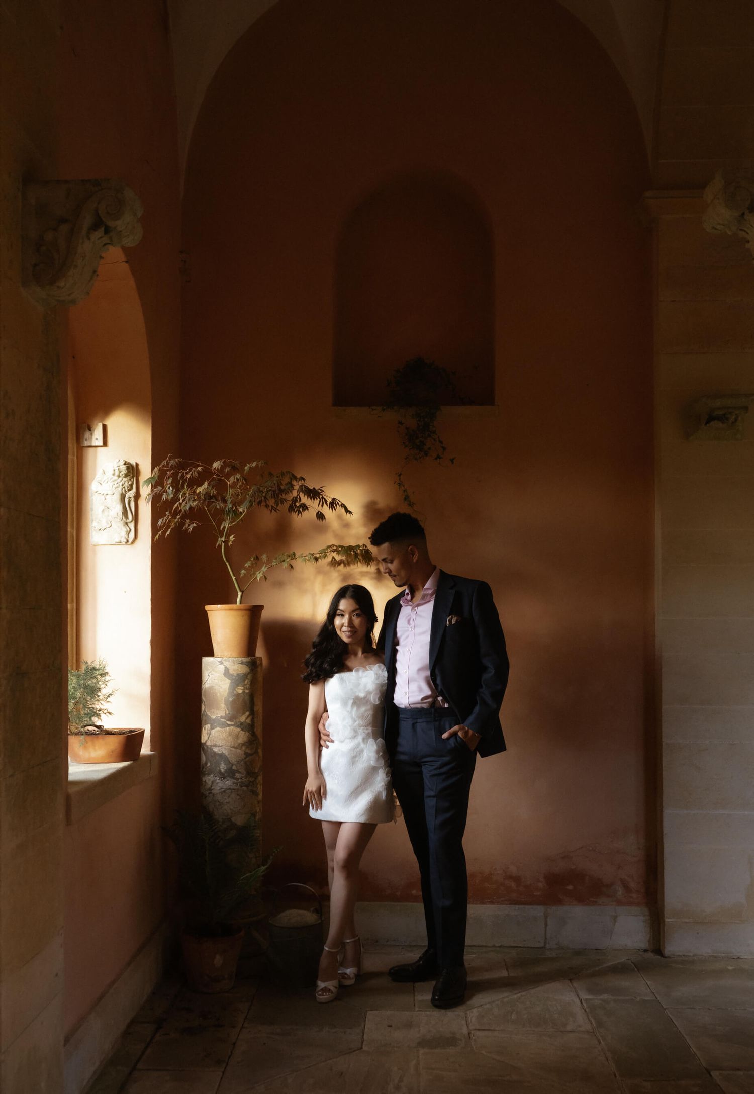 Atmospheric wedding photos captured in a dimly lit stone archway interior.