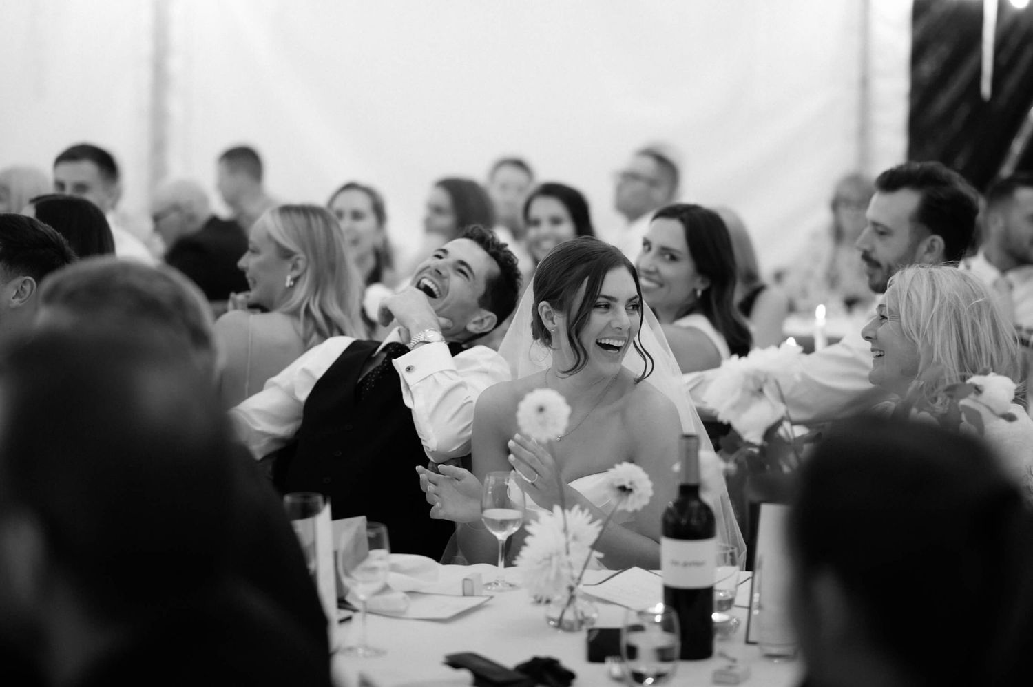 Wedding guests enjoying a reception dinner at tables in an elegant venue.
