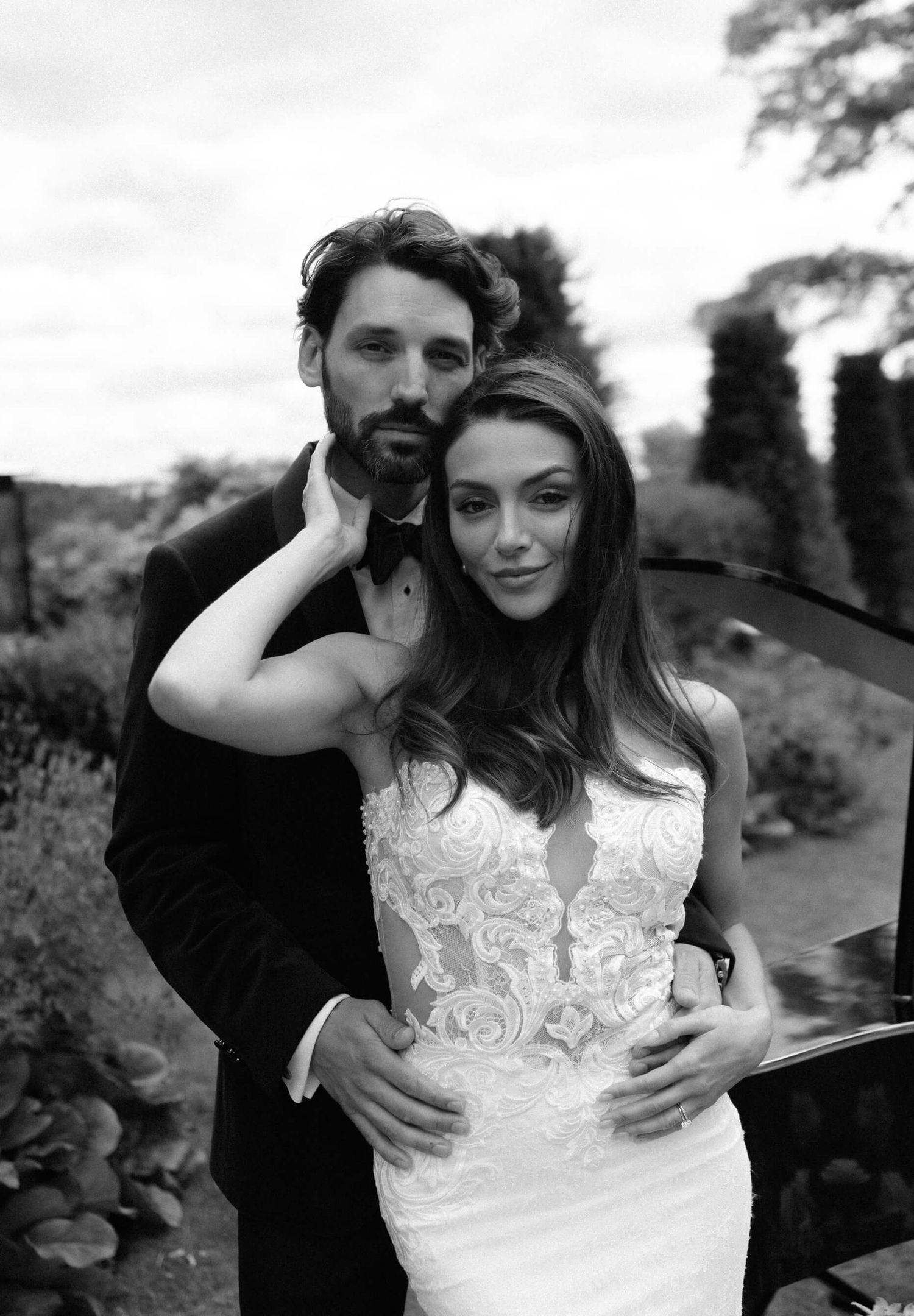 Artistic black and white wedding portraits showing intimate moments between newlyweds in a garden setting.