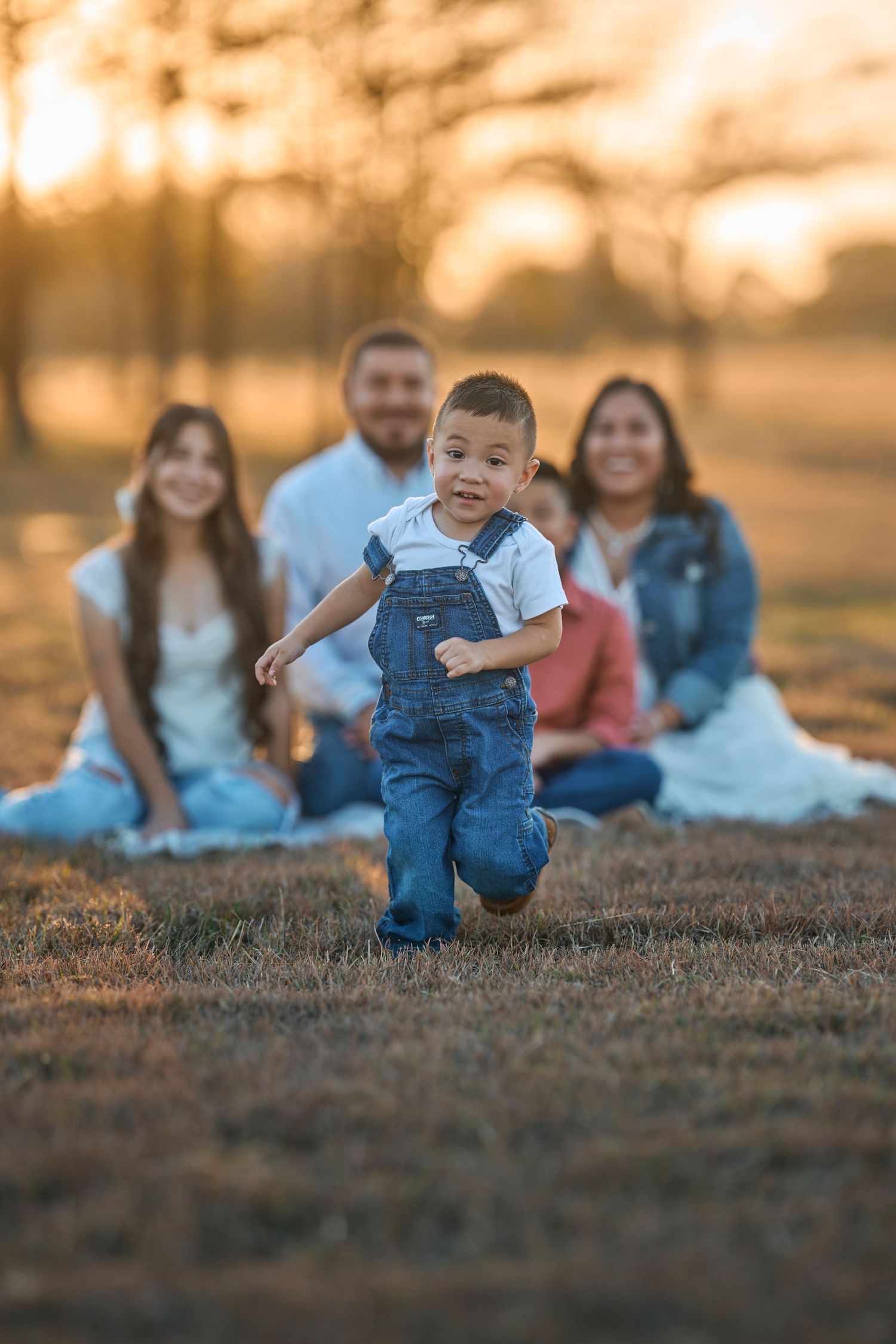 Family gathering on grassy field during golden sunset hour.