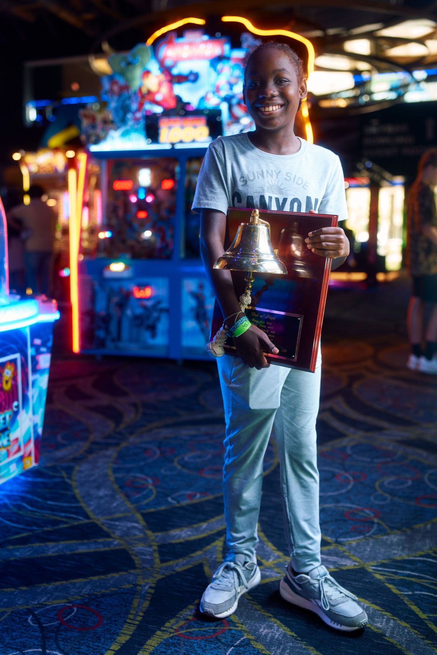 Arcade scene showing colorful neon lights and carpeted floor with someone holding game tokens.