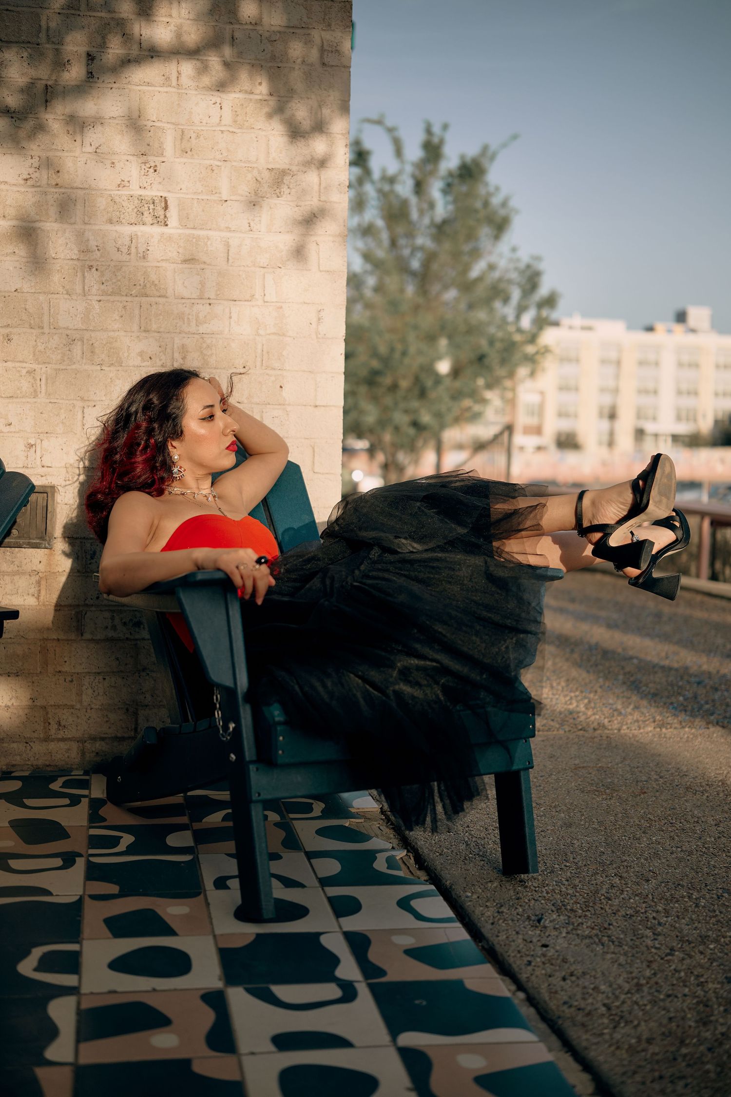 A person in a black tulle dress reclines dramatically across outdoor benches in a series of artistic poses.