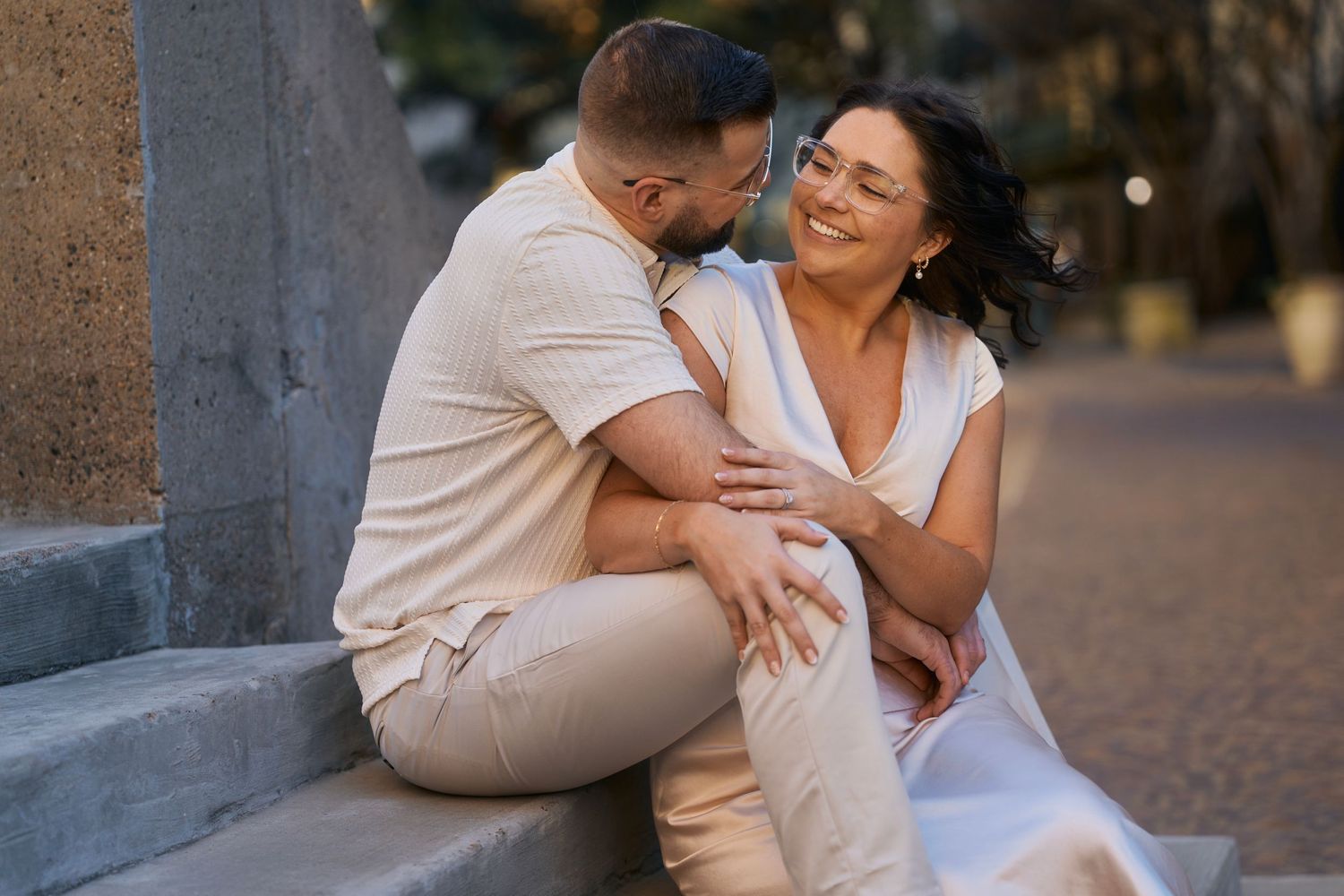 A couple shares a tender moment while sitting together outdoors during golden hour.