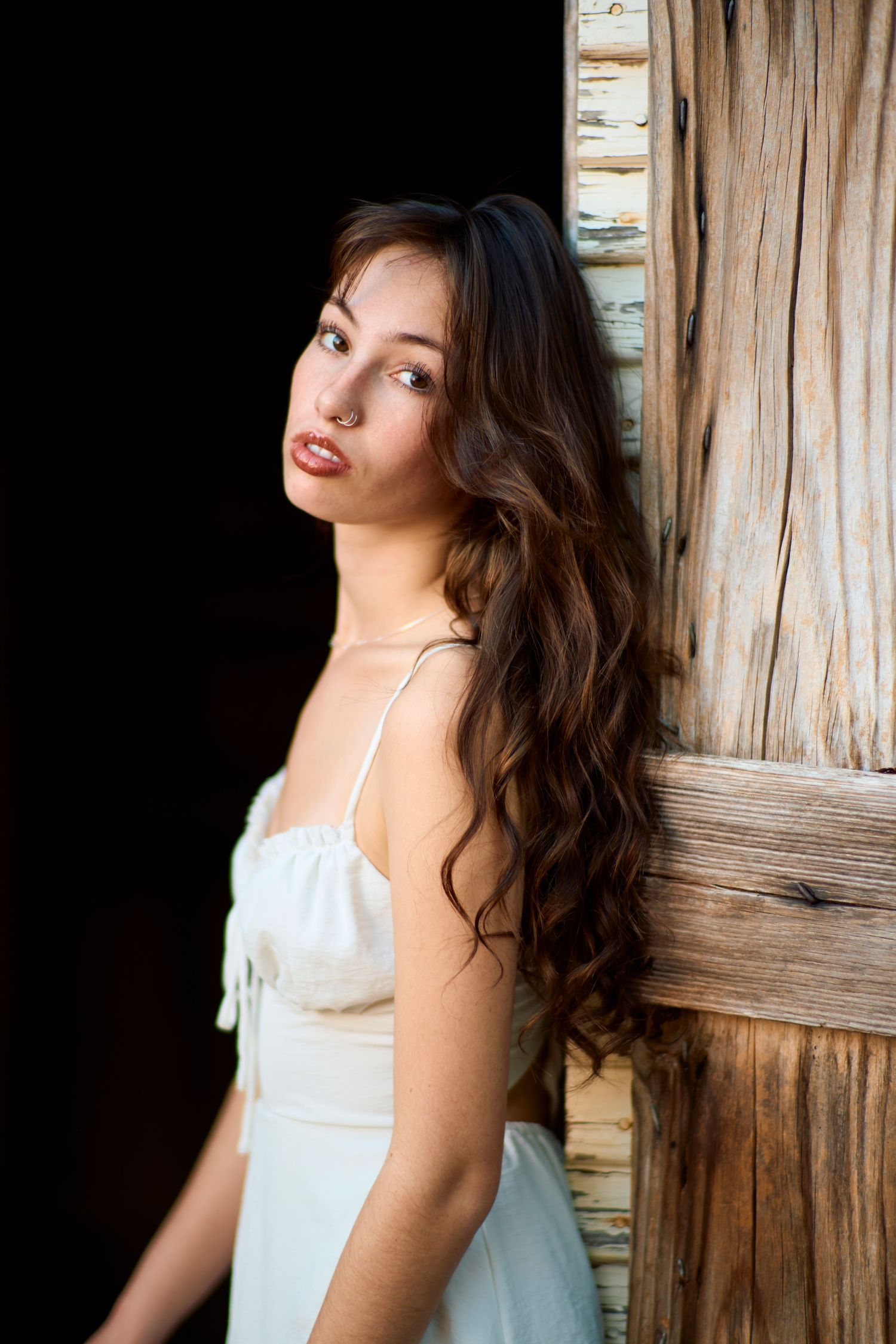 Portrait series against a rustic wooden wall in natural lighting.