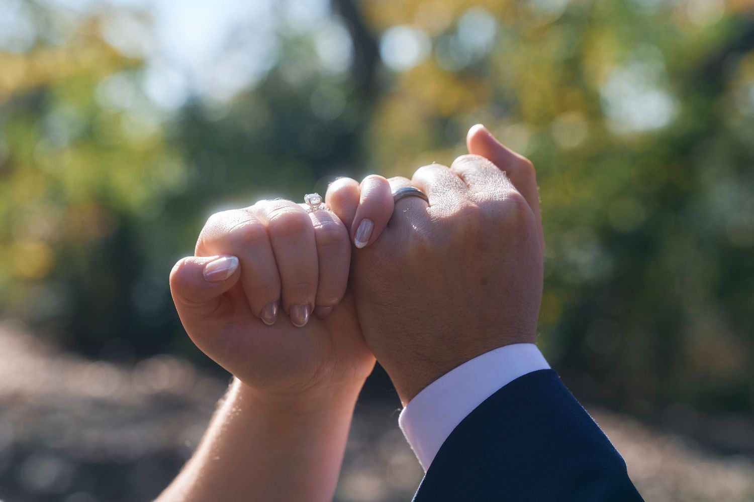 Close-up of hands tenderly touching against blurred natural background.