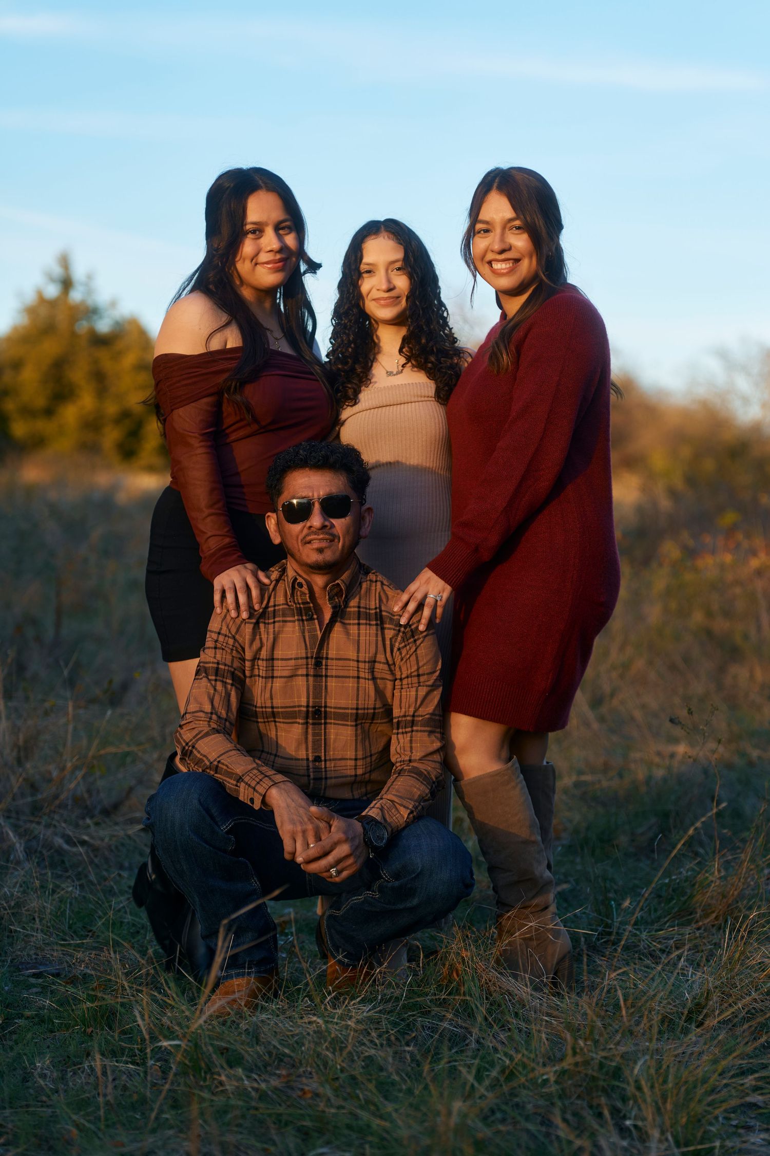 Family group posing together in casual attire during golden hour outdoor photoshoot.