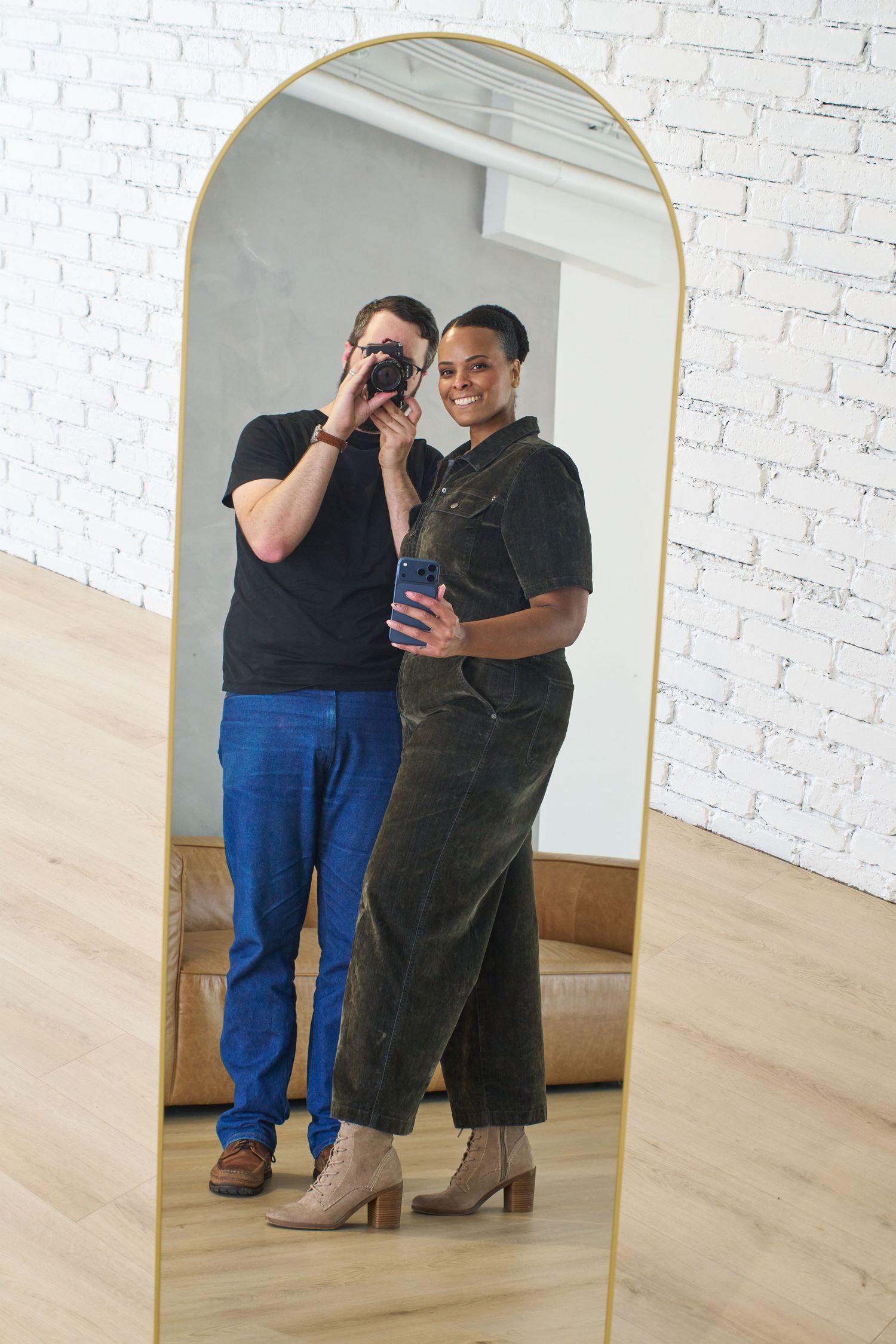 Two people dancing together in a bright studio with white brick walls and wooden floors.
