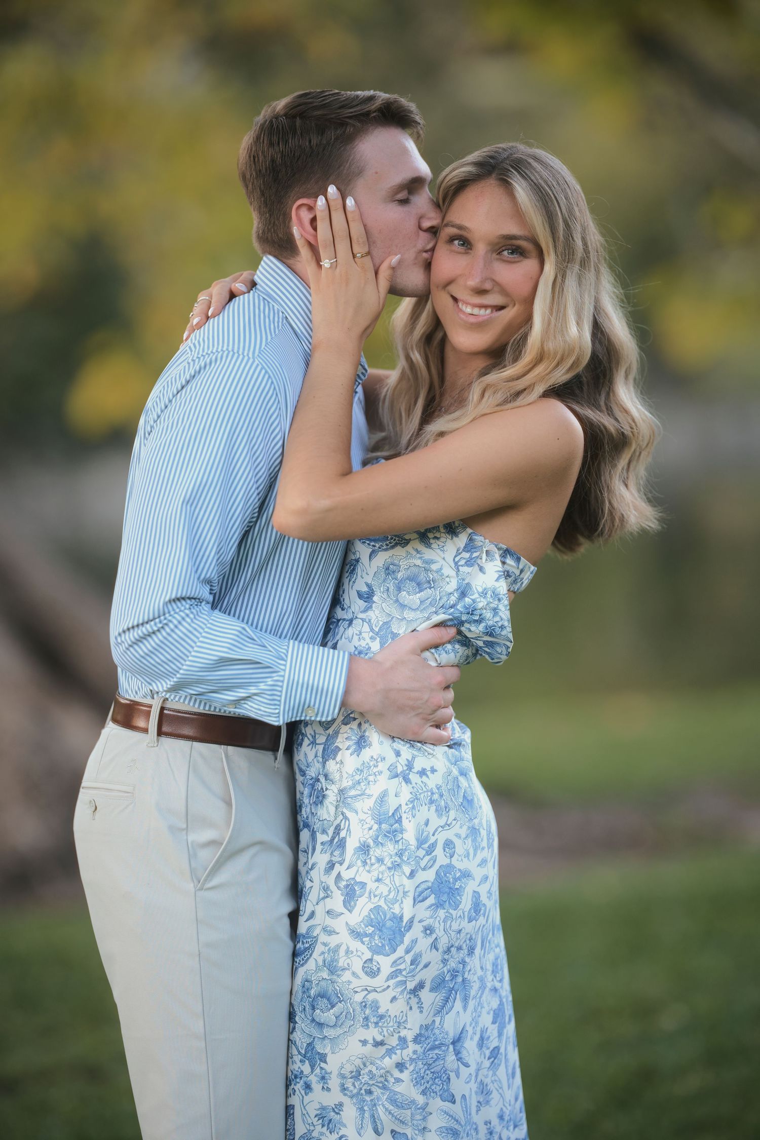 Couple sharing a romantic moment in a blue and white floral dress and light colored outfit outdoors.
