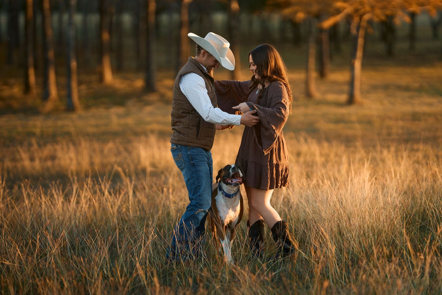 A couple embraces in a golden sunlit field during sunset, creating a romantic autumn atmosphere.