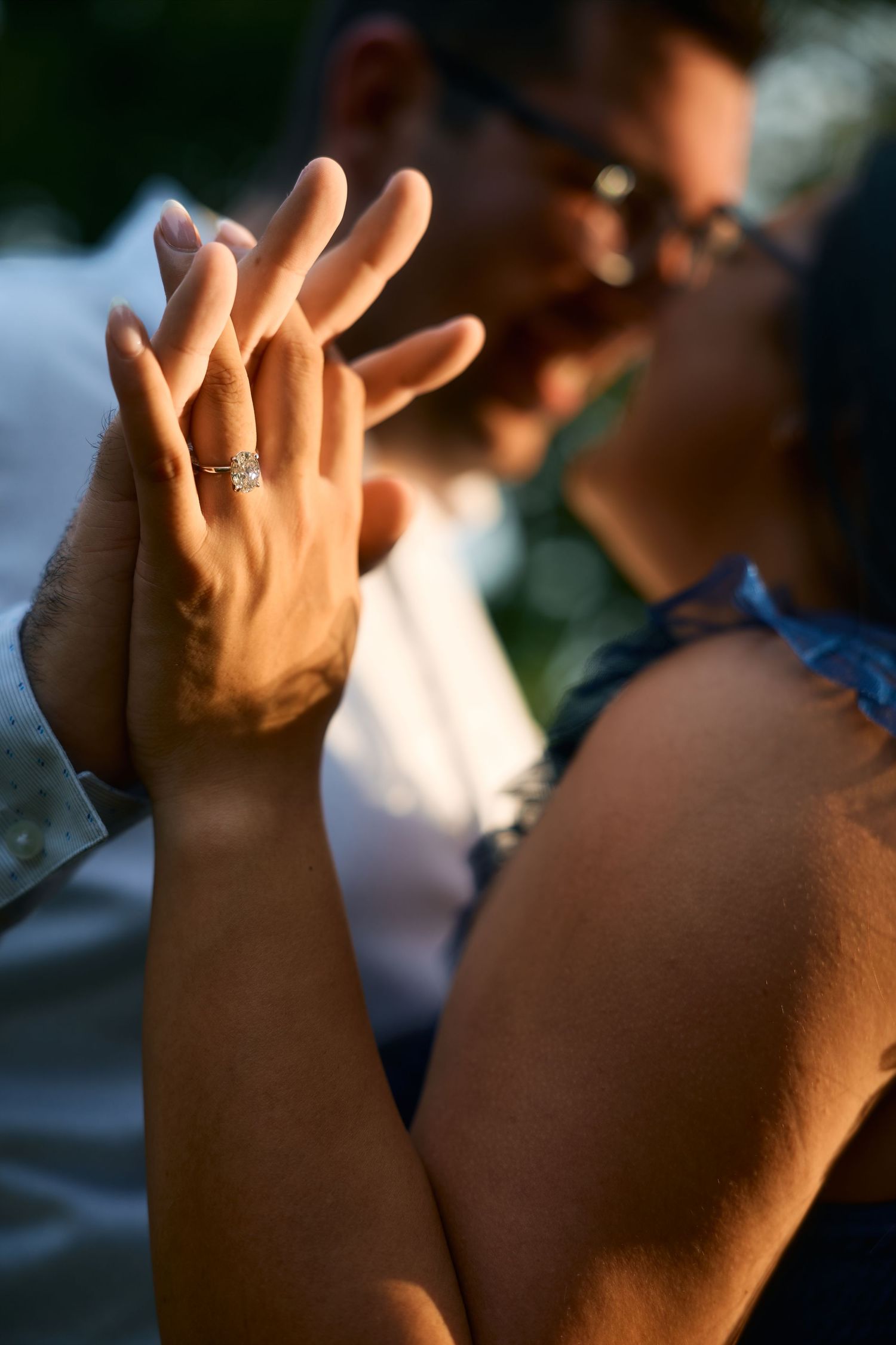 Close-up of hands showing engagement ring during sunset.