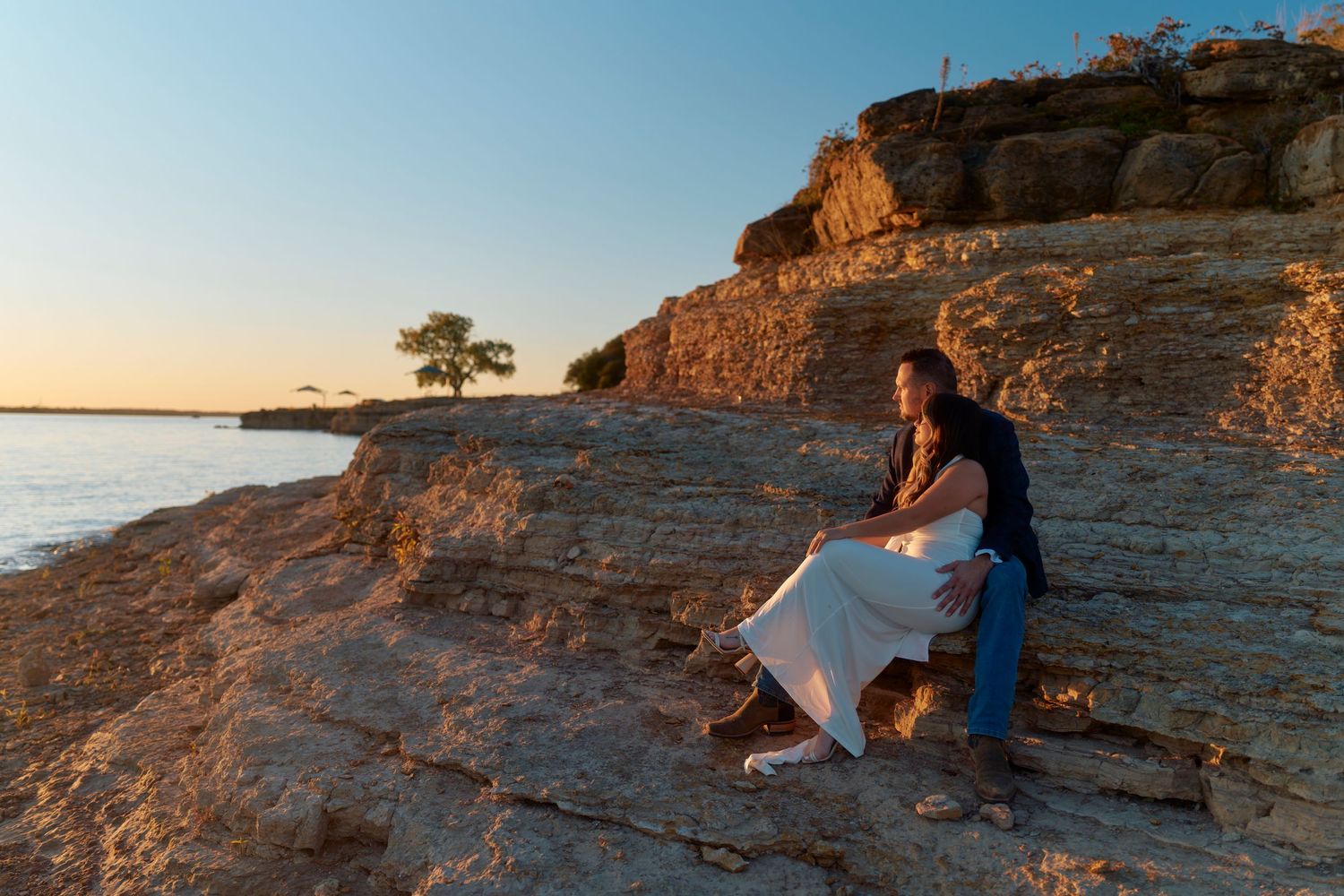People sit on rocky cliffs overlooking a scenic sunset landscape at Horseshoe Bend in Arizona.