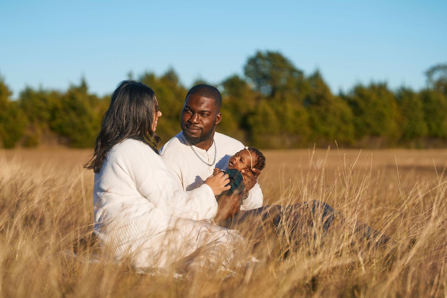 Couple relaxing together in sunlit field with golden grass.