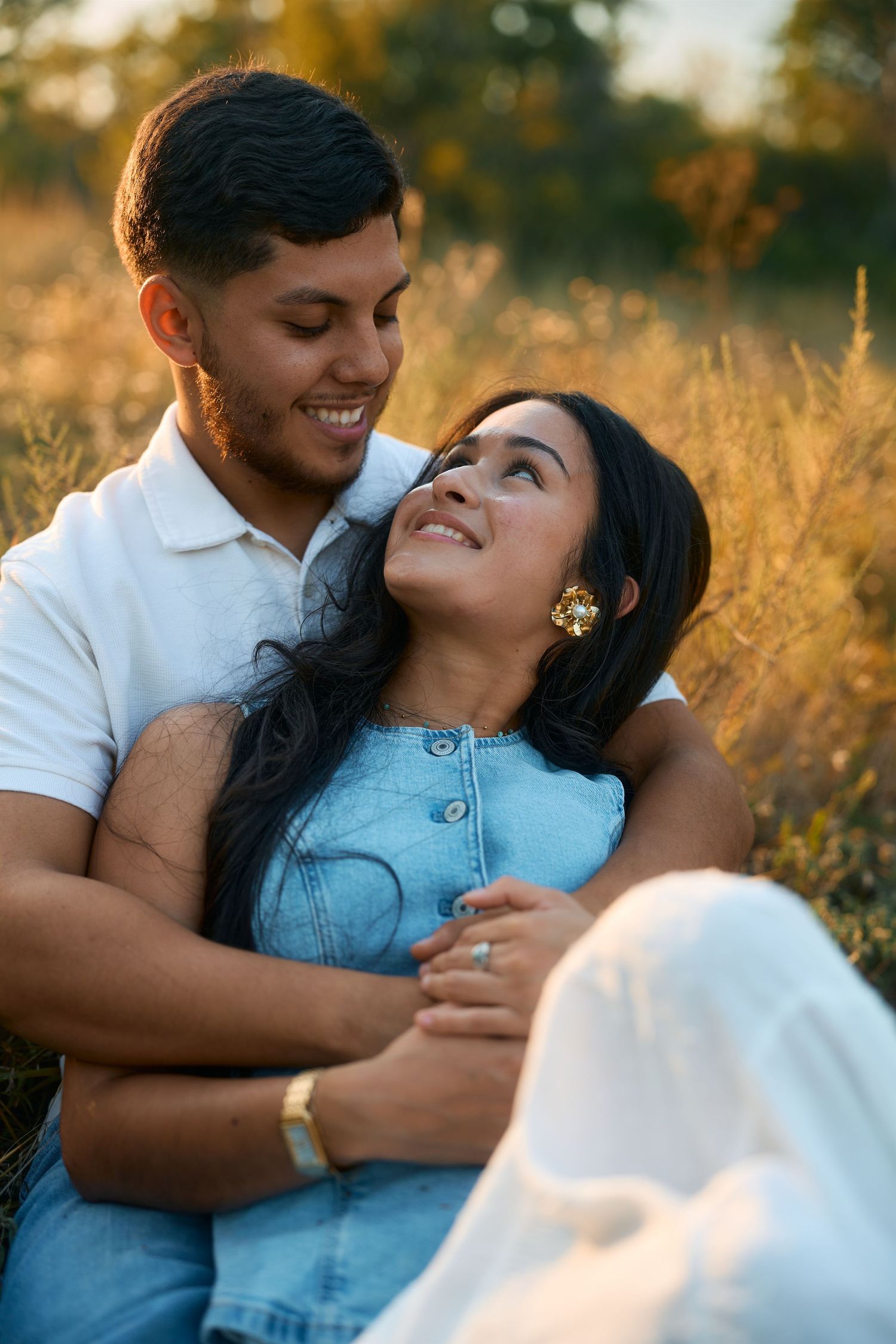 Couple sharing tender moment in golden field during sunset.