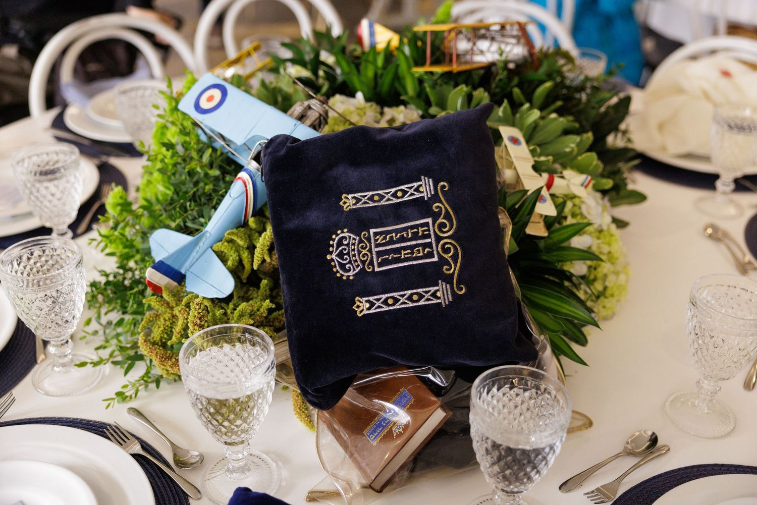 Elegant table setting with crystal glasses, greenery centerpieces and navy blue accents.