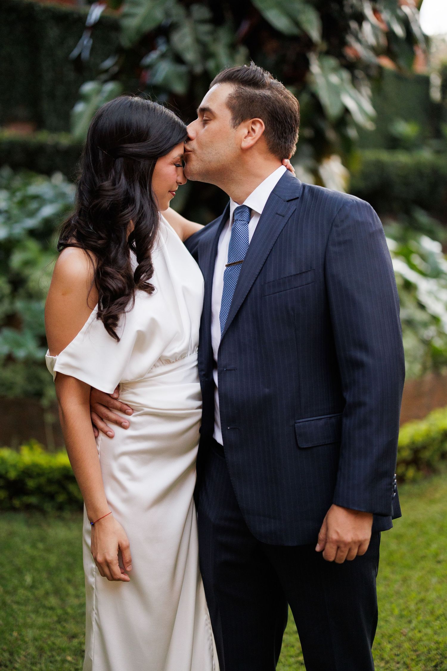 A couple shares an intimate moment in a garden setting during their wedding photoshoot.