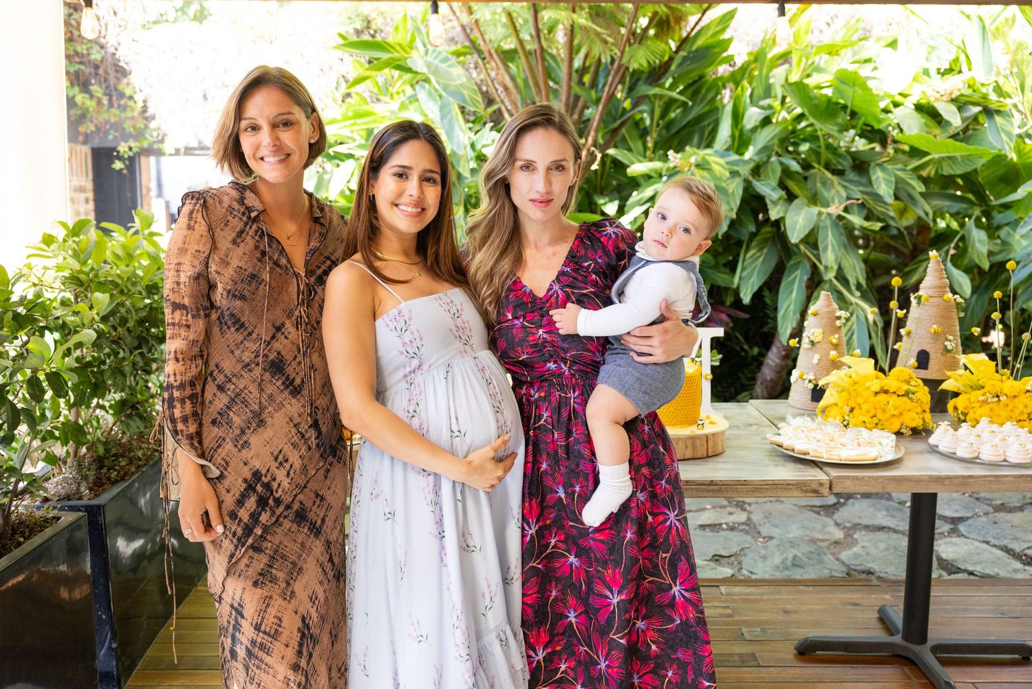 A family photo session in a sunny garden with lush greenery and trees in the background.