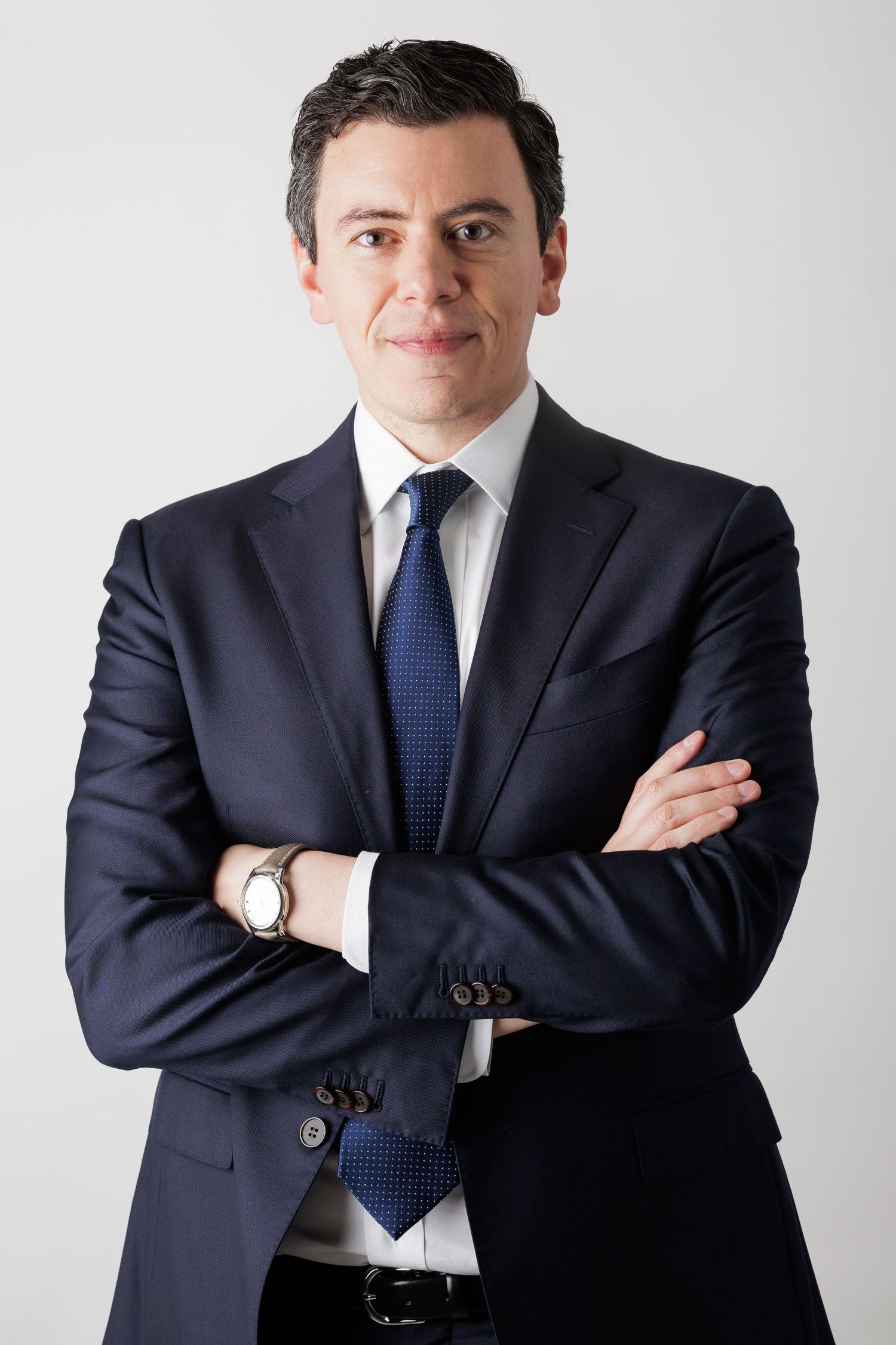 Professional portrait series of someone in navy suit and blue tie against white background.