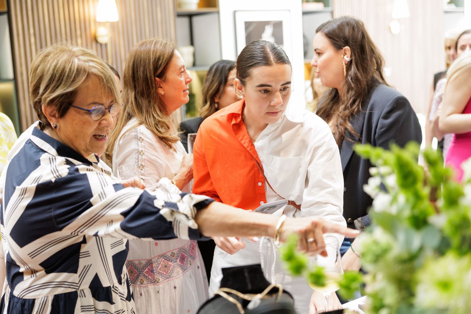 A group of women looking at something together during a social gathering.