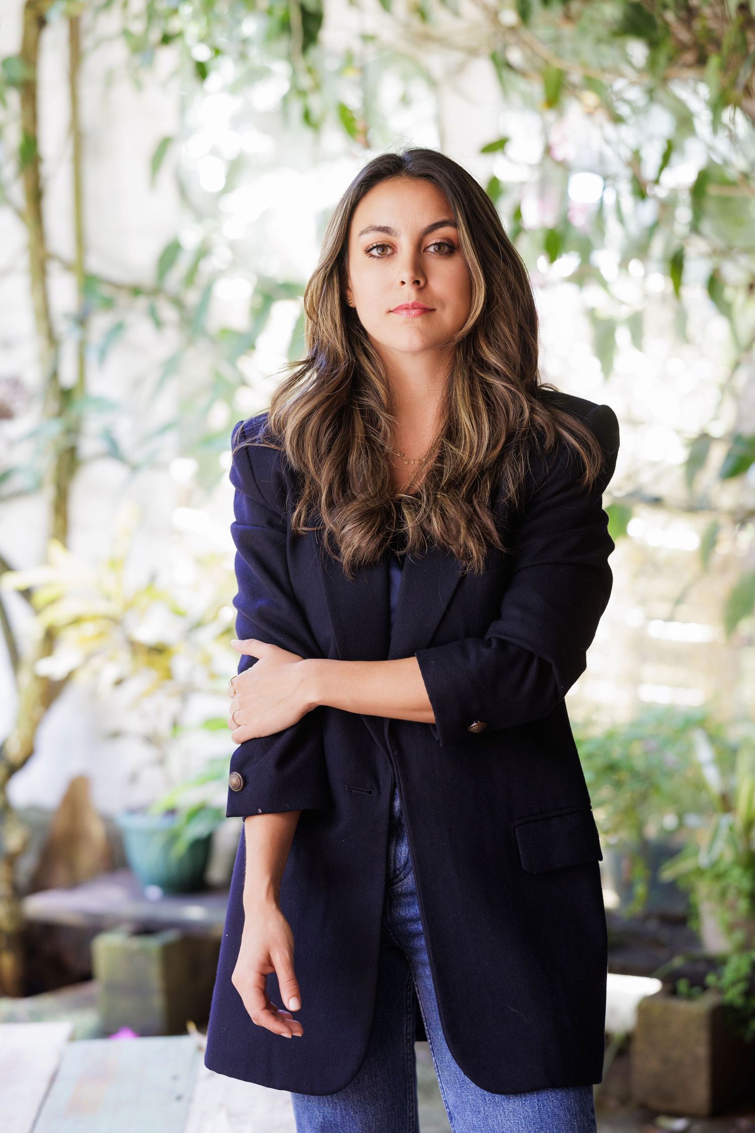 Professional portrait in navy blazer against natural outdoor setting.