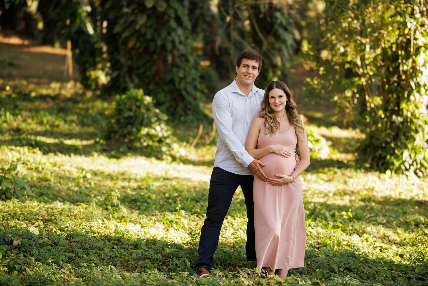 Family maternity photo session in a lush garden setting with golden afternoon light.