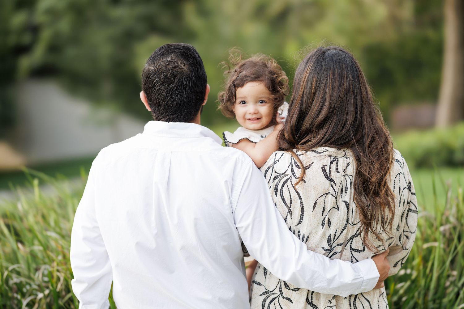 Family members embracing while walking through a garden path.