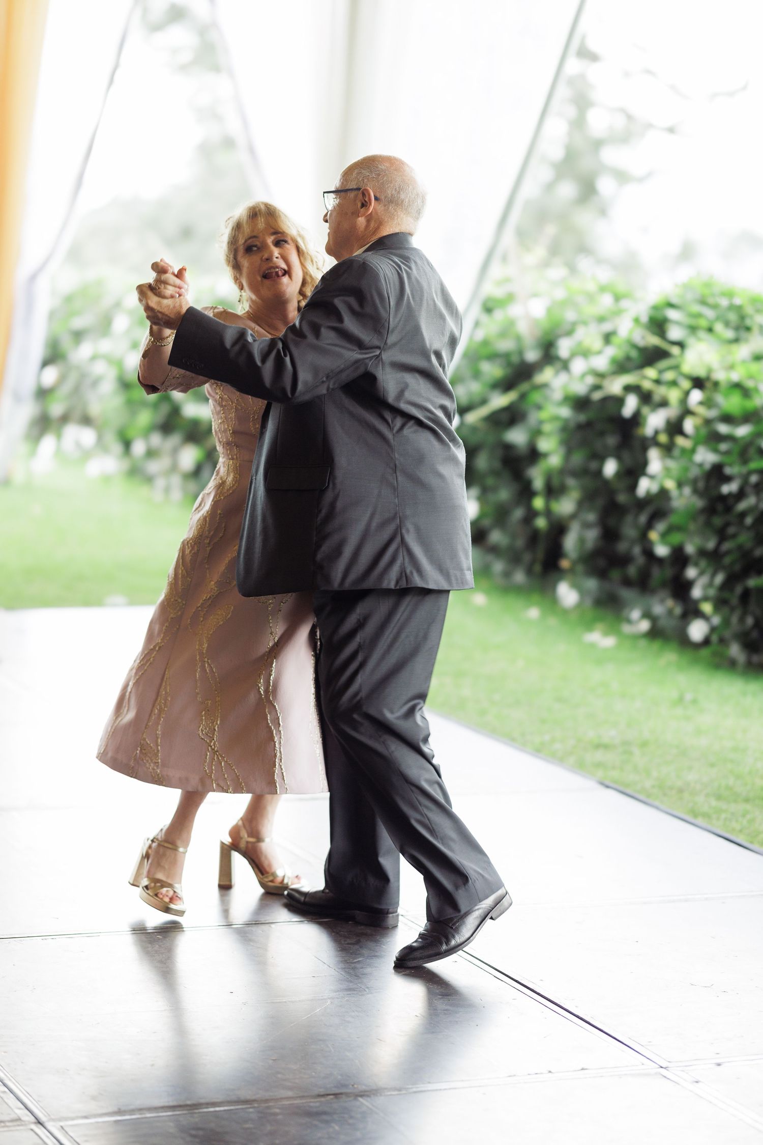 Dance sequence showing joyful movements between two people in formal attire on a light-filled porch.