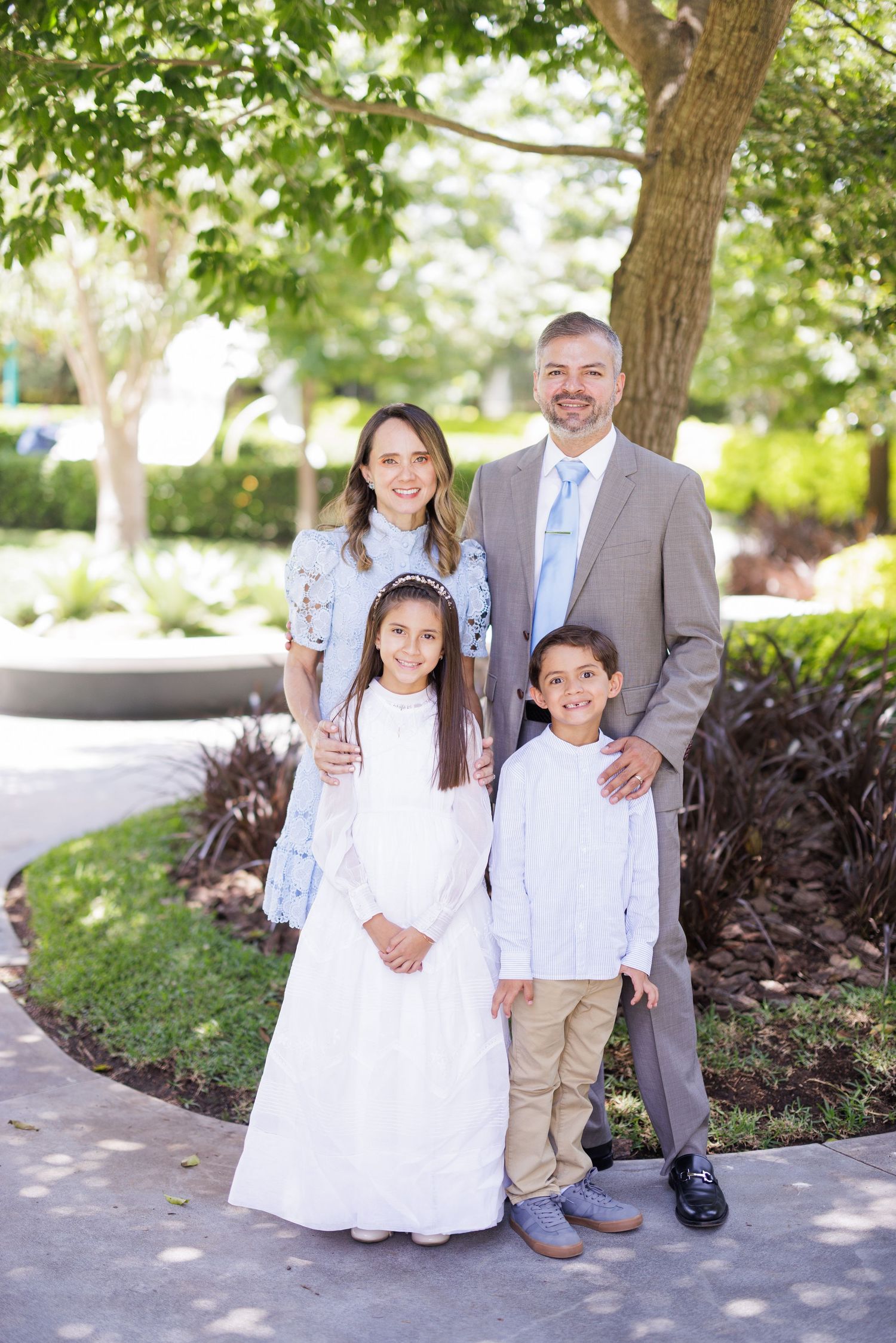 Family members in coordinated formal attire pose together in an outdoor garden setting.