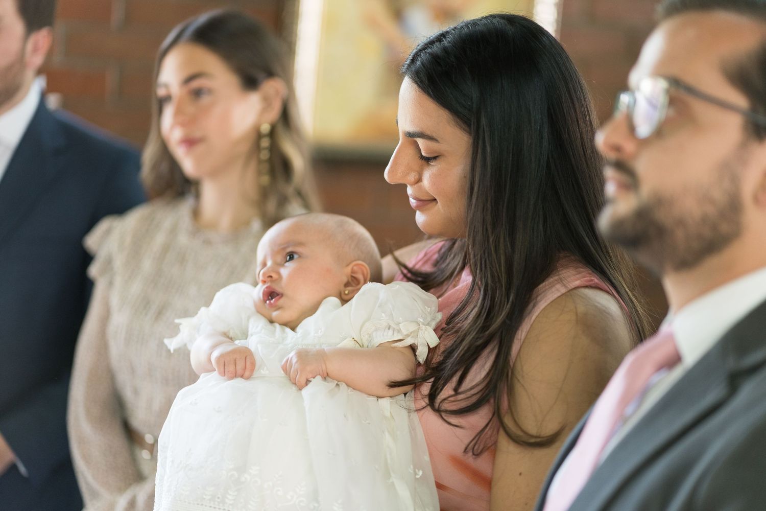 A christening ceremony gathering in a church with traditional white baptismal gown.