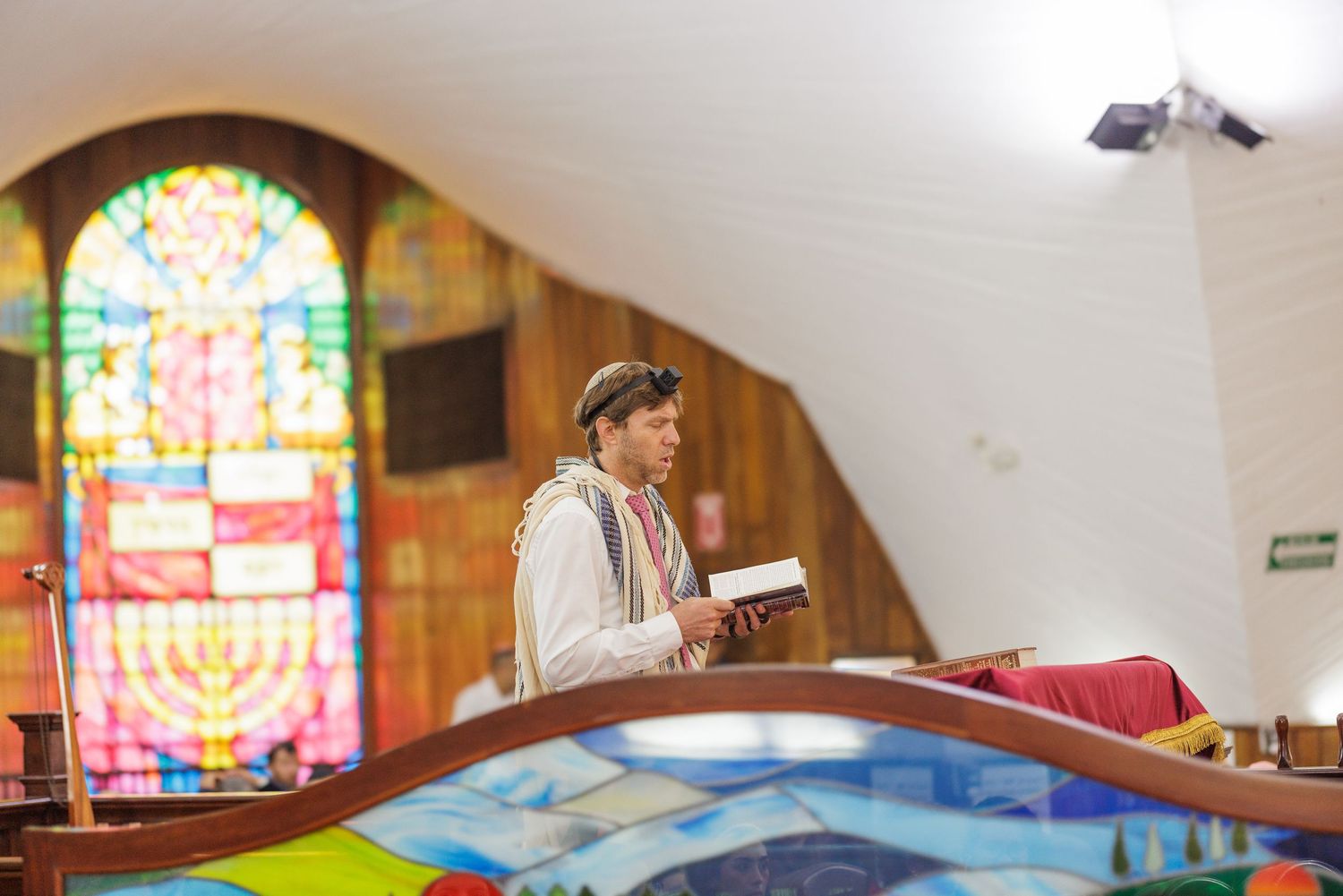 Interior of a church or chapel with colorful stained glass windows and wooden pews.