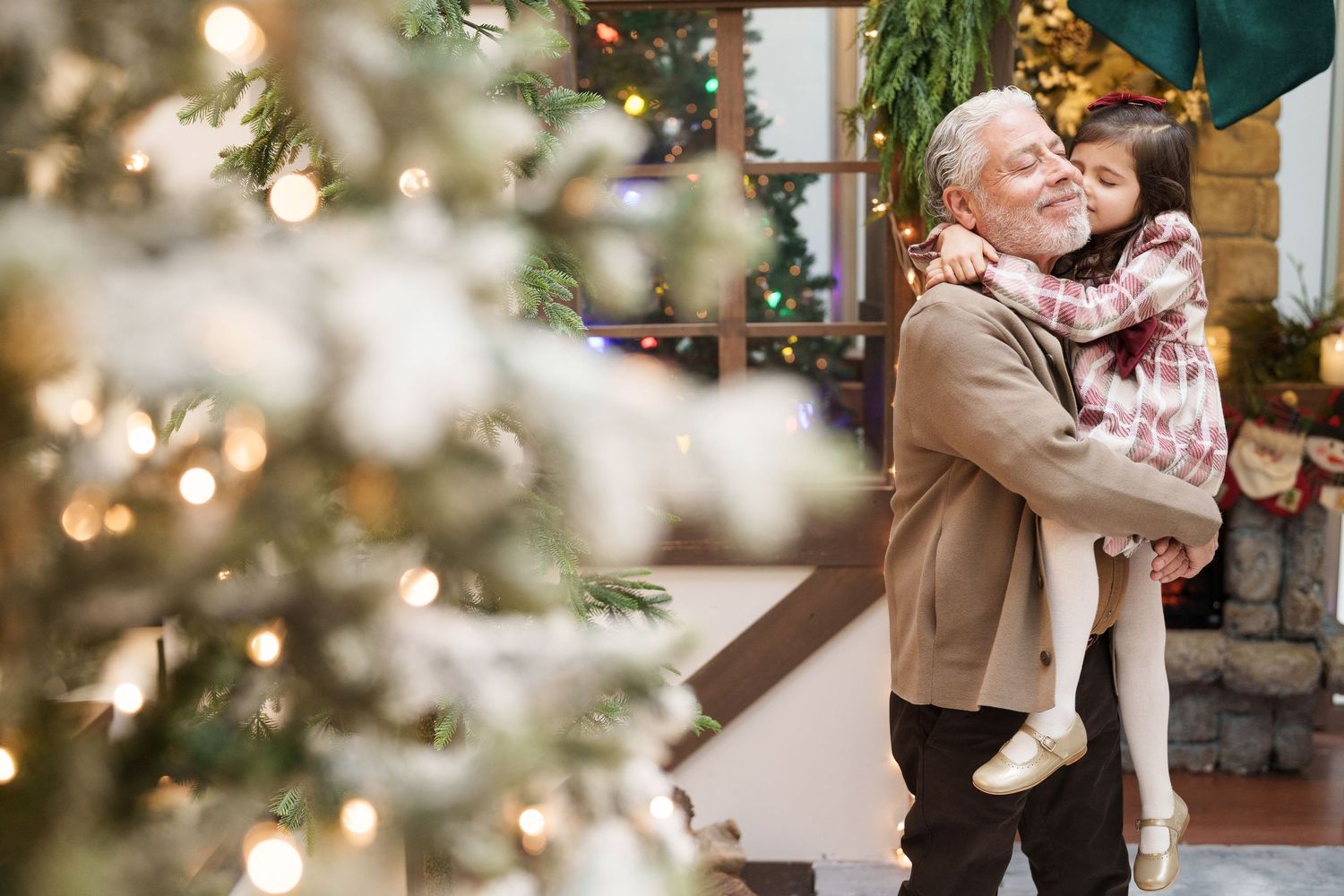 A heartwarming embrace shared beside a glowing Christmas tree with bokeh lights.