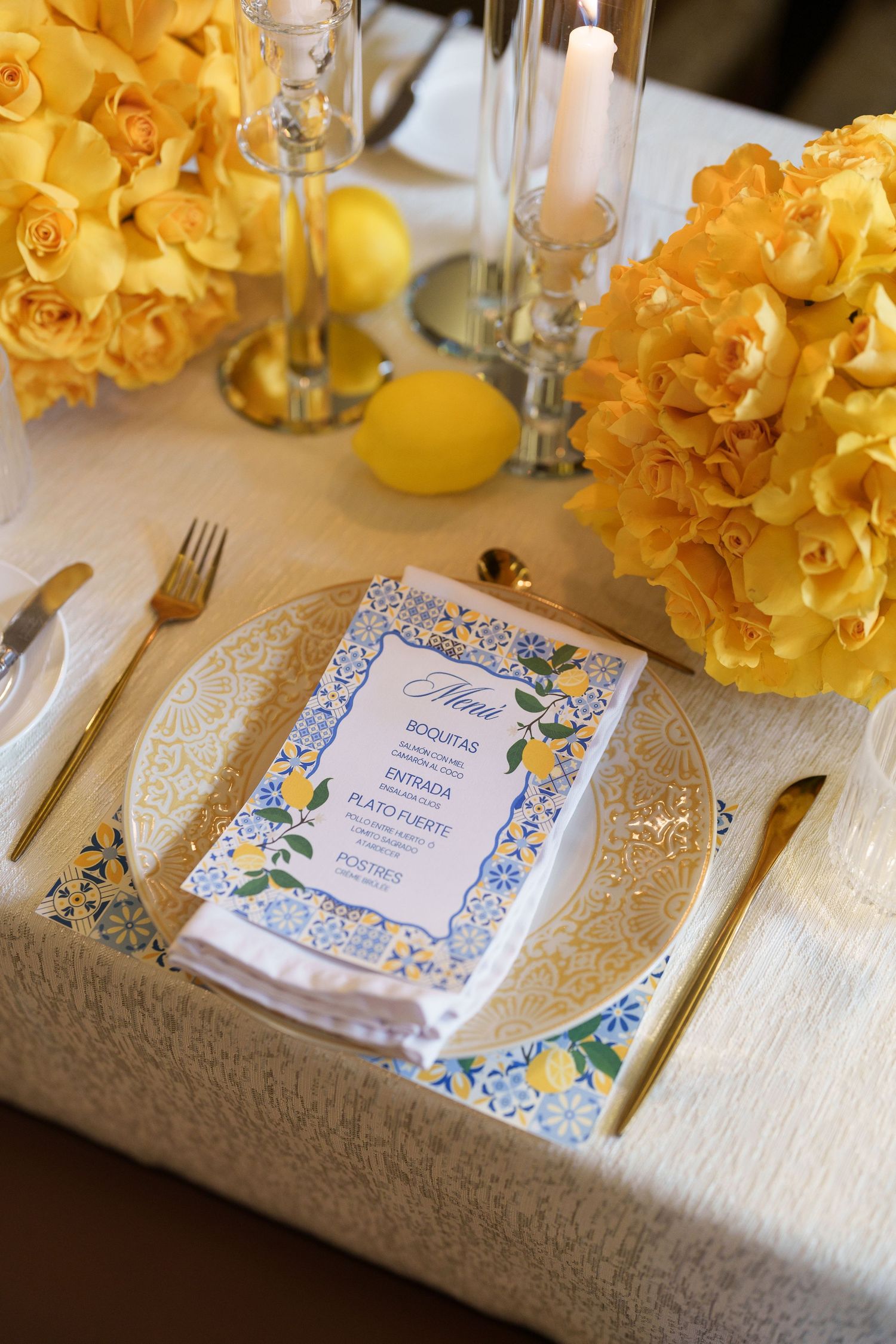 Yellow floral centerpieces and elegant place settings with blue and white menu cards on a formal dining table.