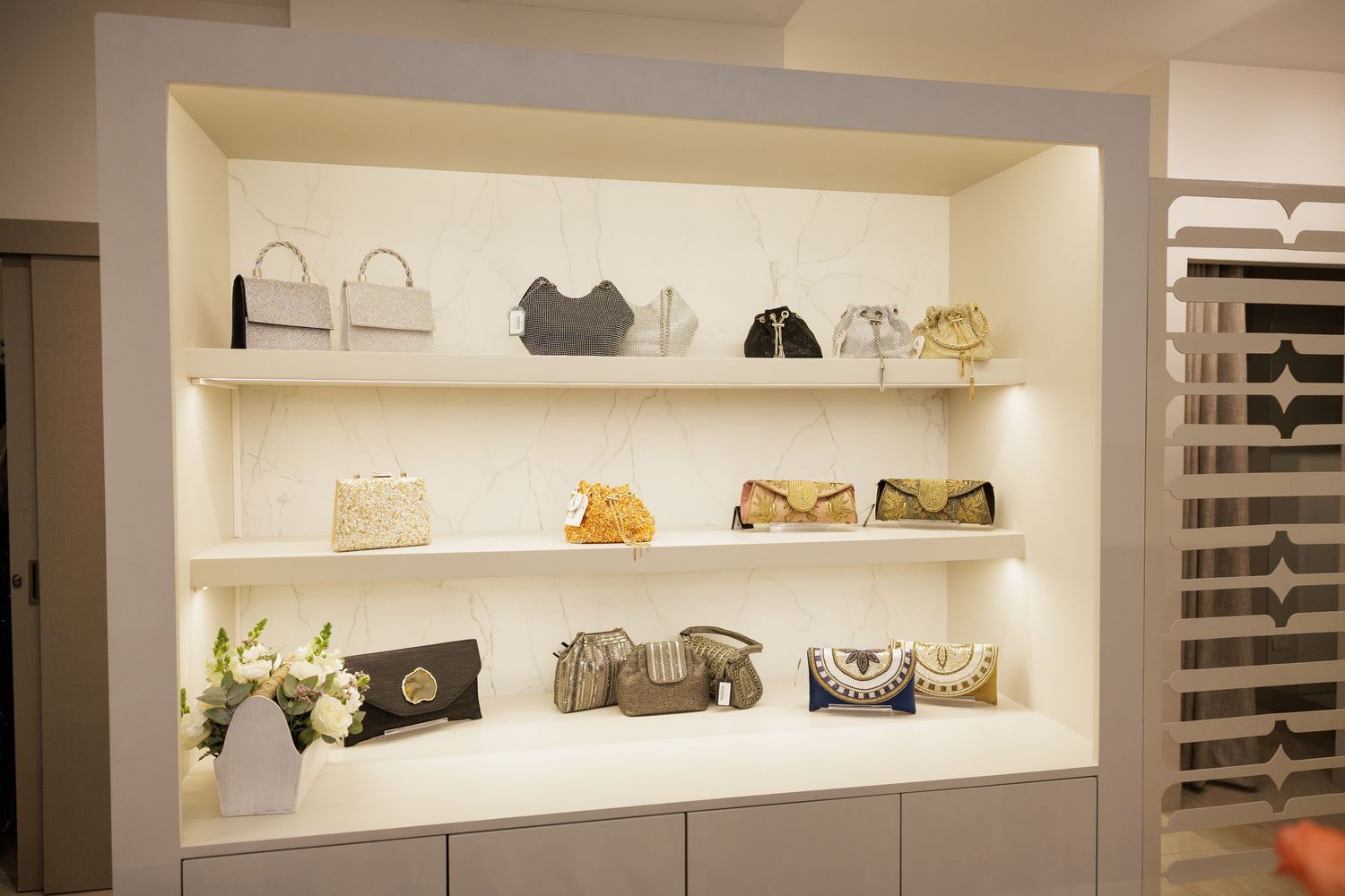 Illuminated display shelves showcase luxury handbags and accessories in a modern retail boutique.