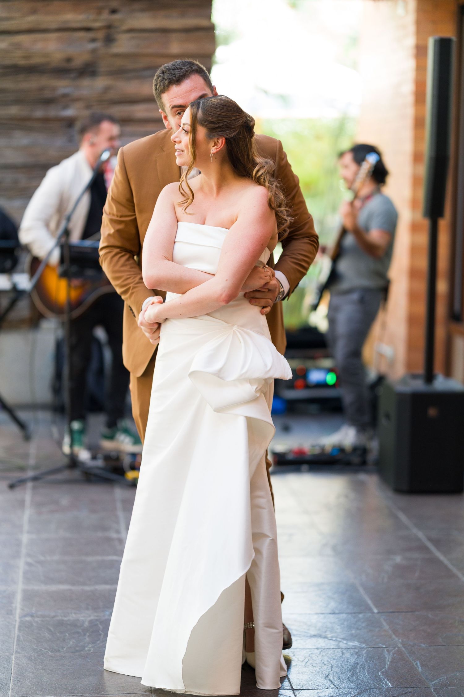A couple shares an intimate dance moment at their wedding reception with rustic decor.