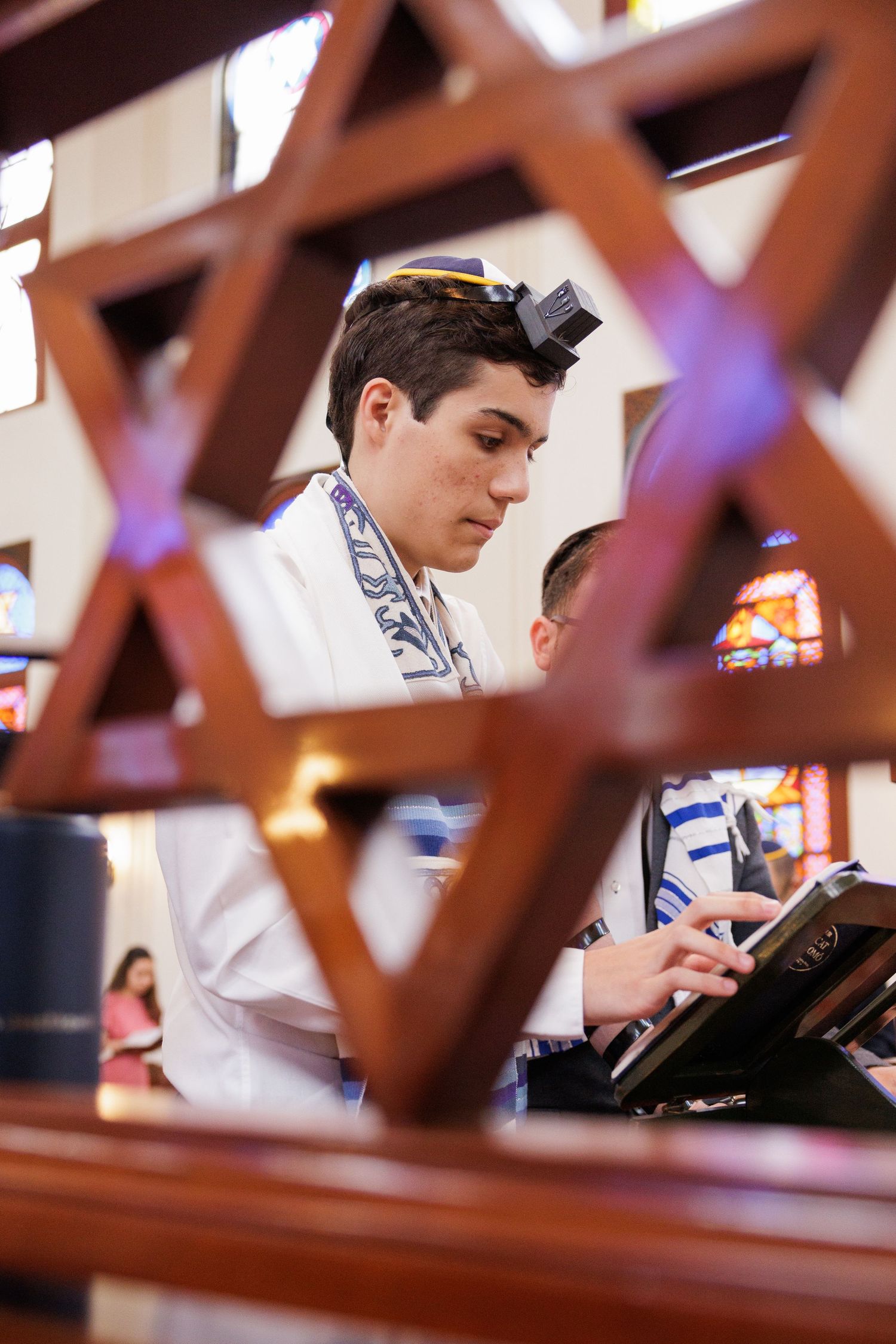 Close-up view through wooden synagogue pews during a religious service.
