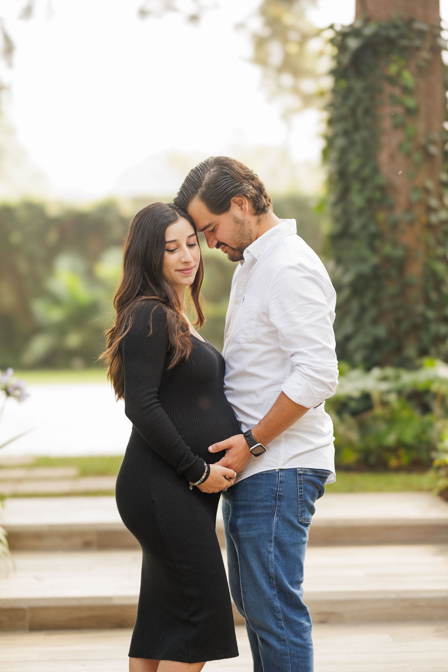 Maternity photo session showing tender moments between couple outdoors.
